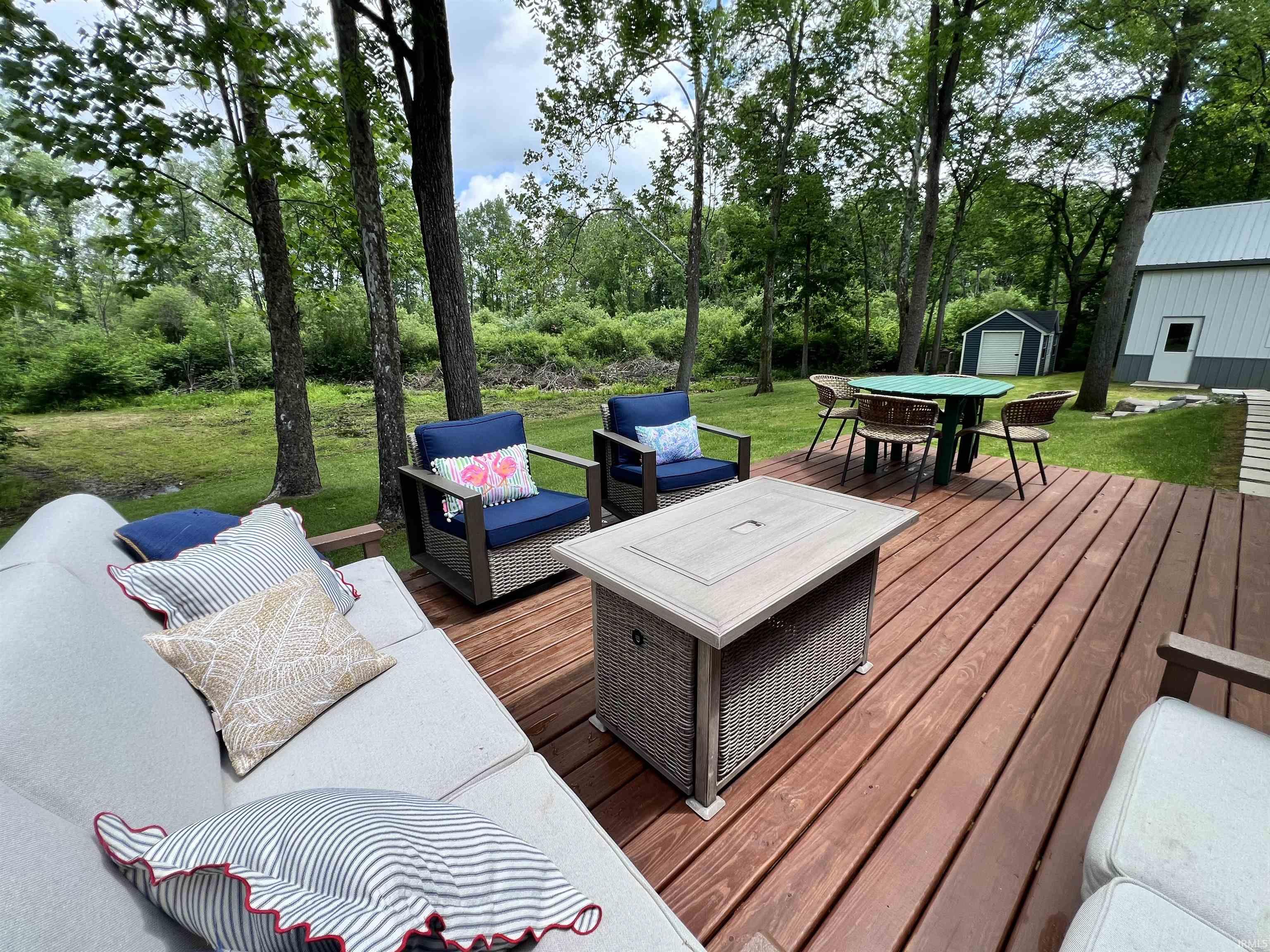Expansive wood deck with a built-in fire pit, surrounded by mature trees