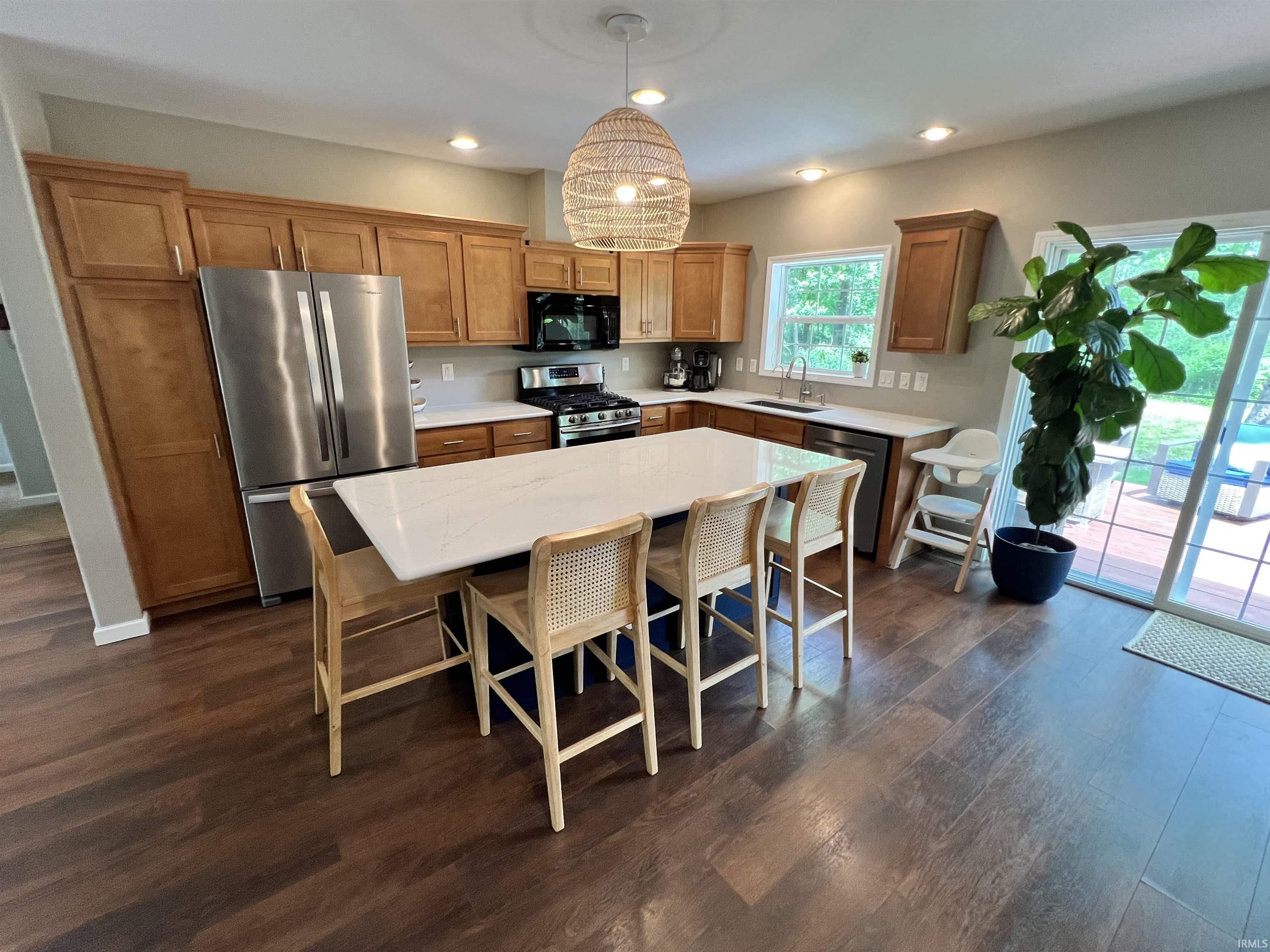 Spacious kitchen featuring an expansive island with a white countertop, recessed lighting, wood-finish flooring, and light wood cabinetry