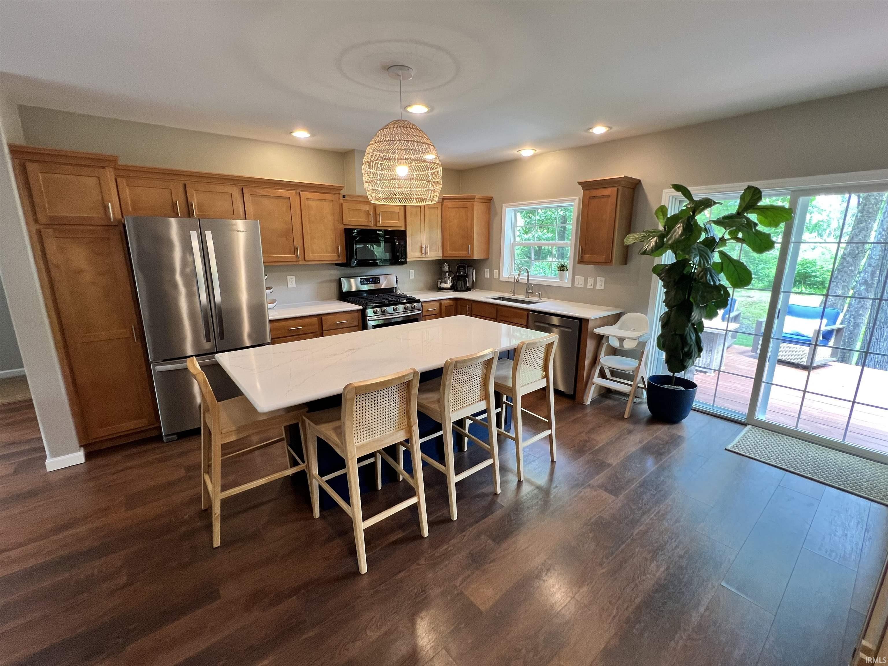 Spacious kitchen featuring wood-finish flooring, light wood cabinetry, and stainless steel appliances