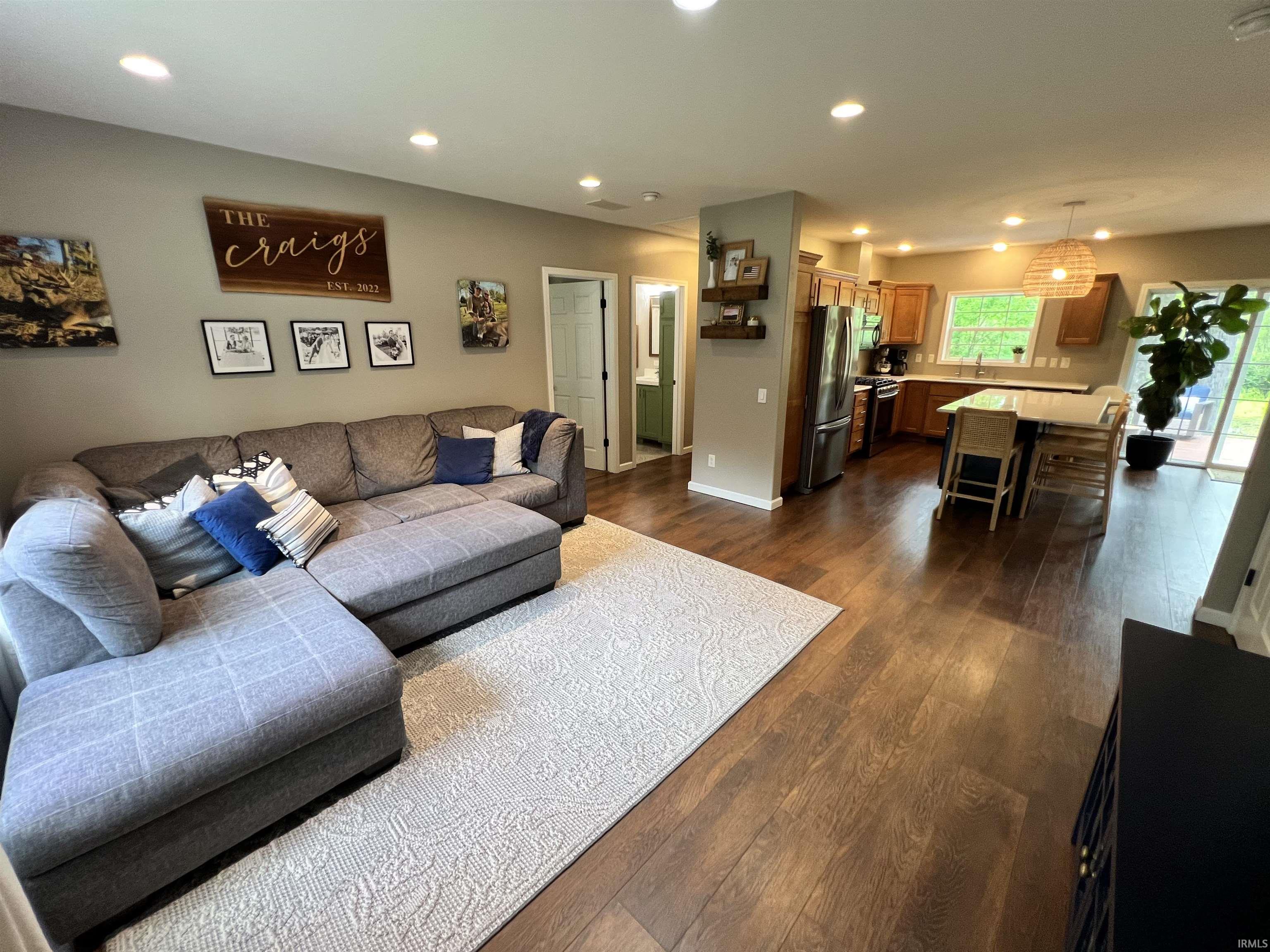 Open-concept living space featuring wood-finish flooring, recessed lighting, and a modern kitchen with stainless steel appliances