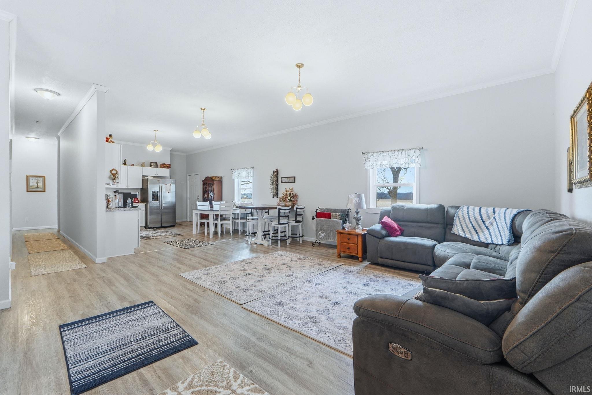 Open-concept living space featuring wood-finish flooring, white walls, and crown molding