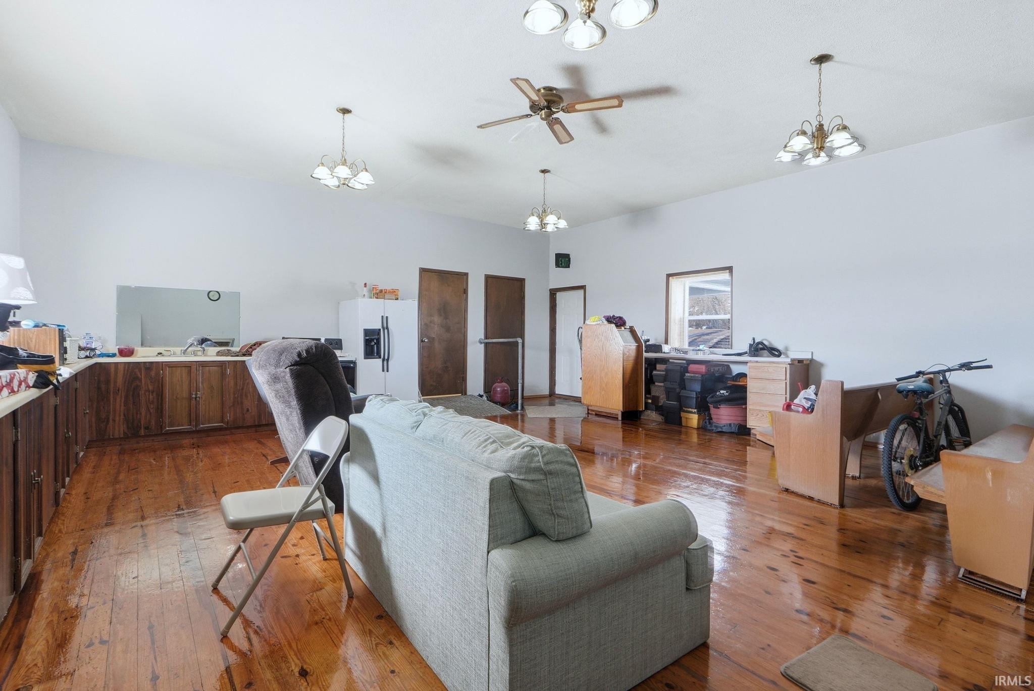 Spacious interior featuring wood-finish flooring, white walls, and a ceiling fan