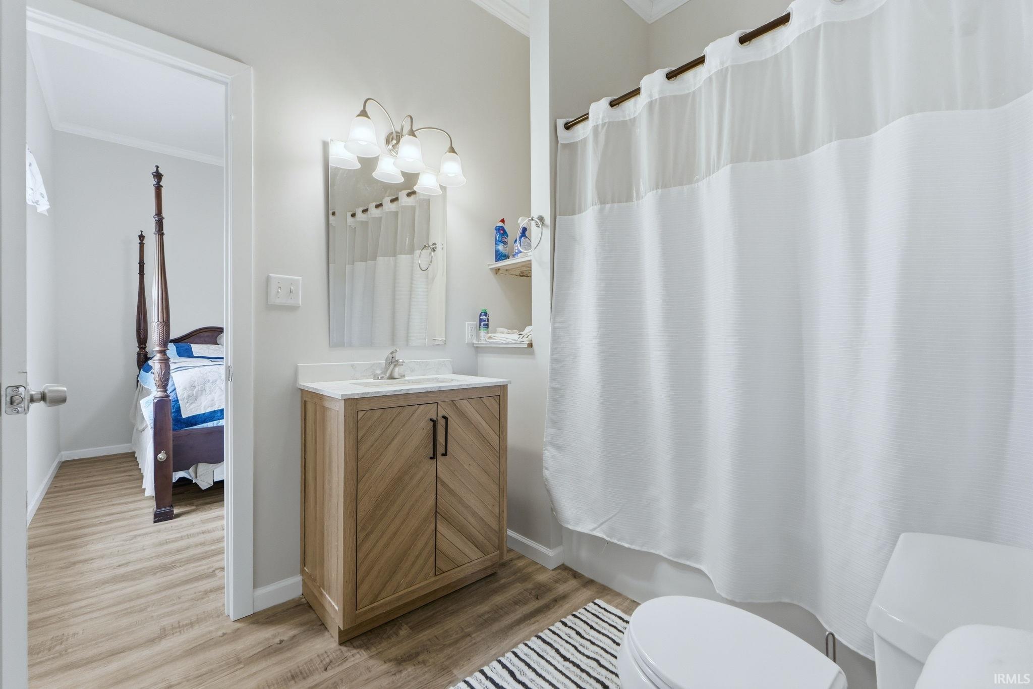 Bathroom featuring wood-finish flooring, a vanity with wood-finish cabinetry, a white countertop, and a shower/tub combination