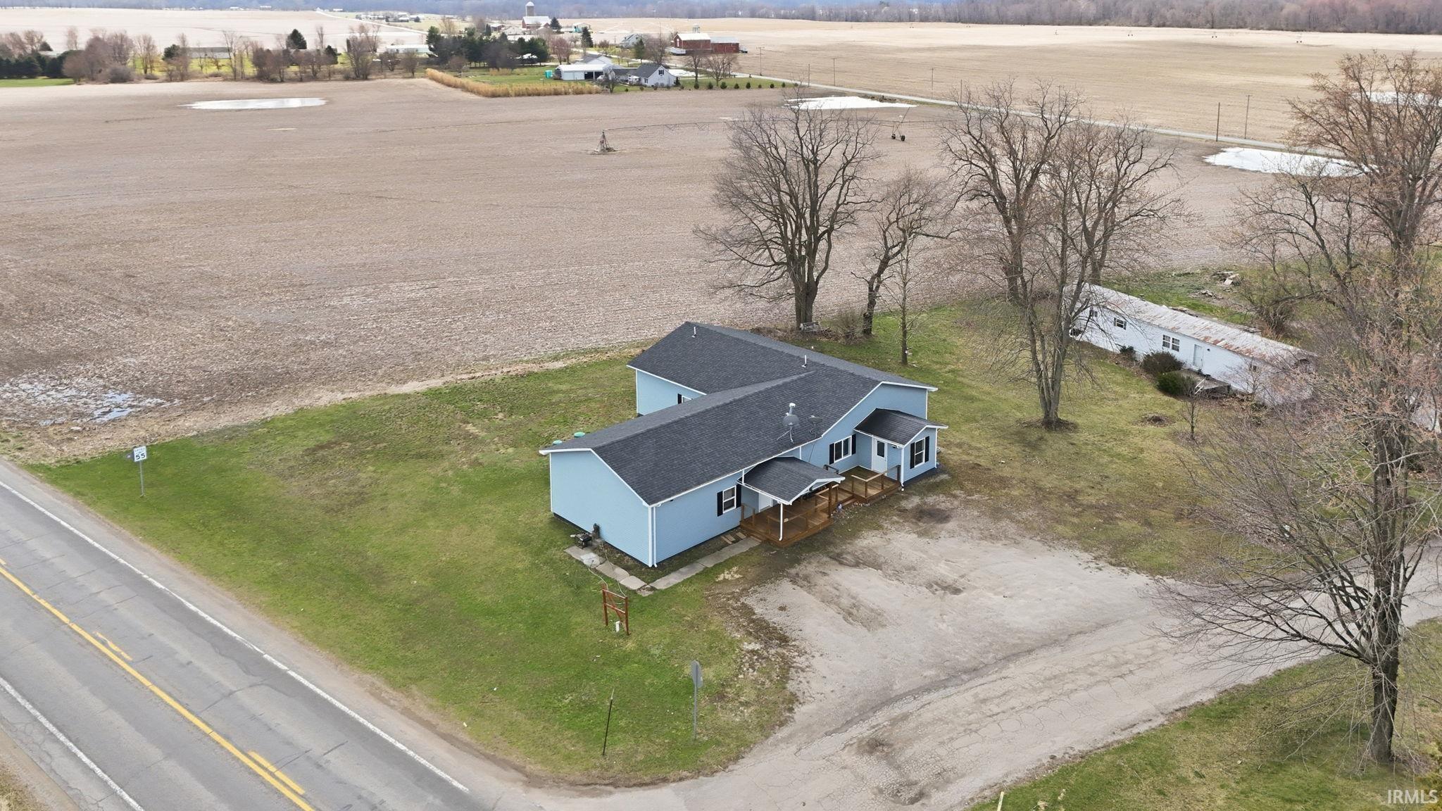 Light blue sided residence with a dark shingle roof and a covered front porch featuring wooden railing