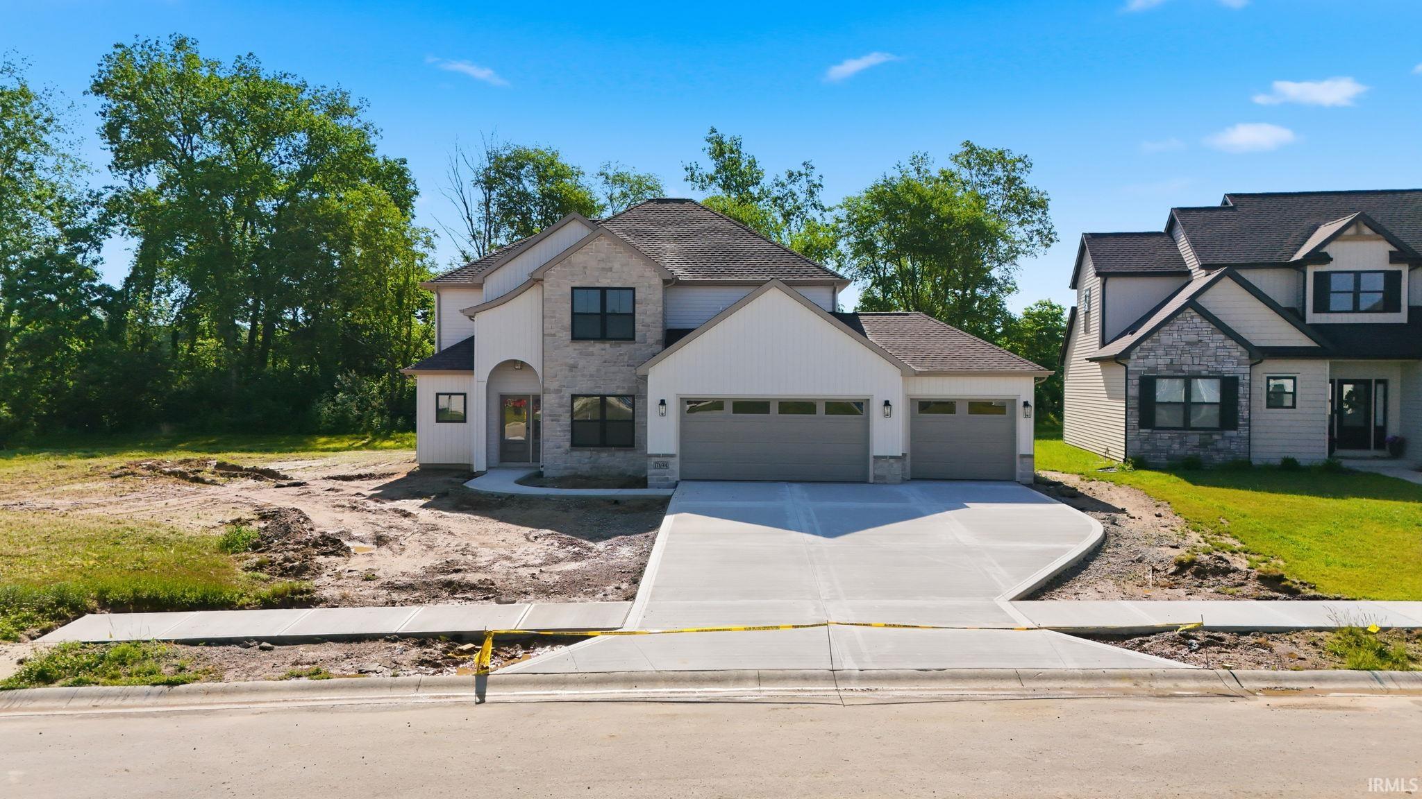 Newly constructed residence with a stone and board and batten facade, featuring a two-car garage