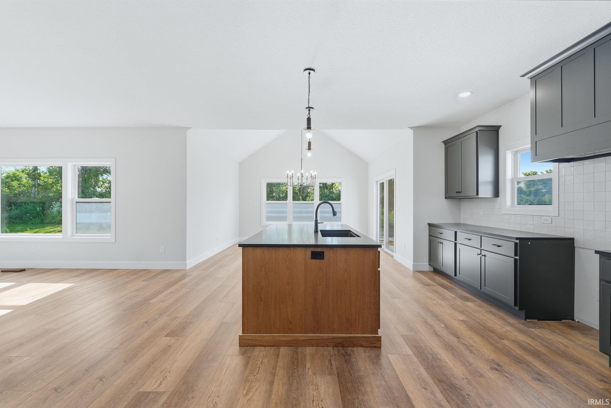 Kitchen island with an undermount sink and matte black faucet, featuring wood-finish cabinetry and a dark countertop