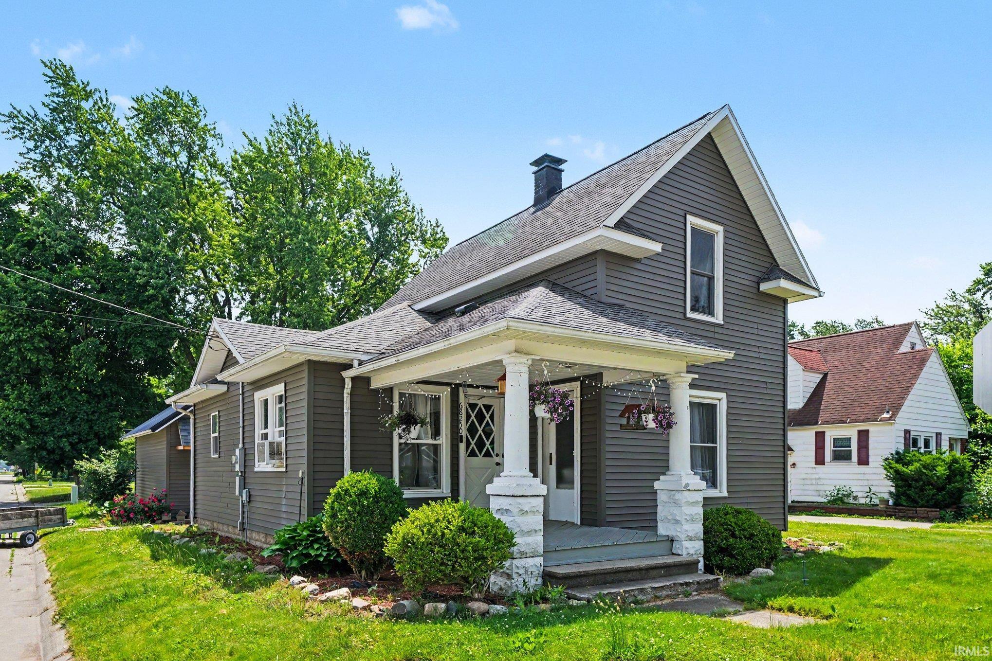 Gray siding exterior with white trim, featuring a covered front porch with white columns