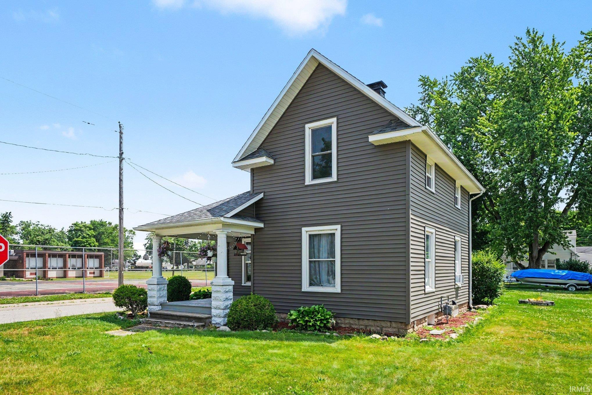 Two-story home with dark gray siding, white trim, and a covered front porch featuring decorative columns