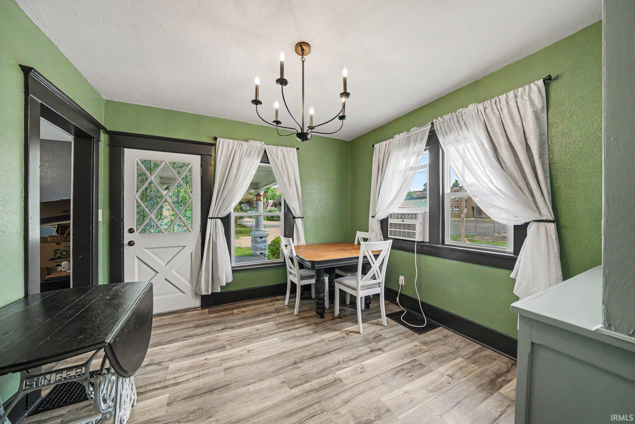 Room featuring wood-finish flooring, a white paneled door with leaded glass, and dark trim