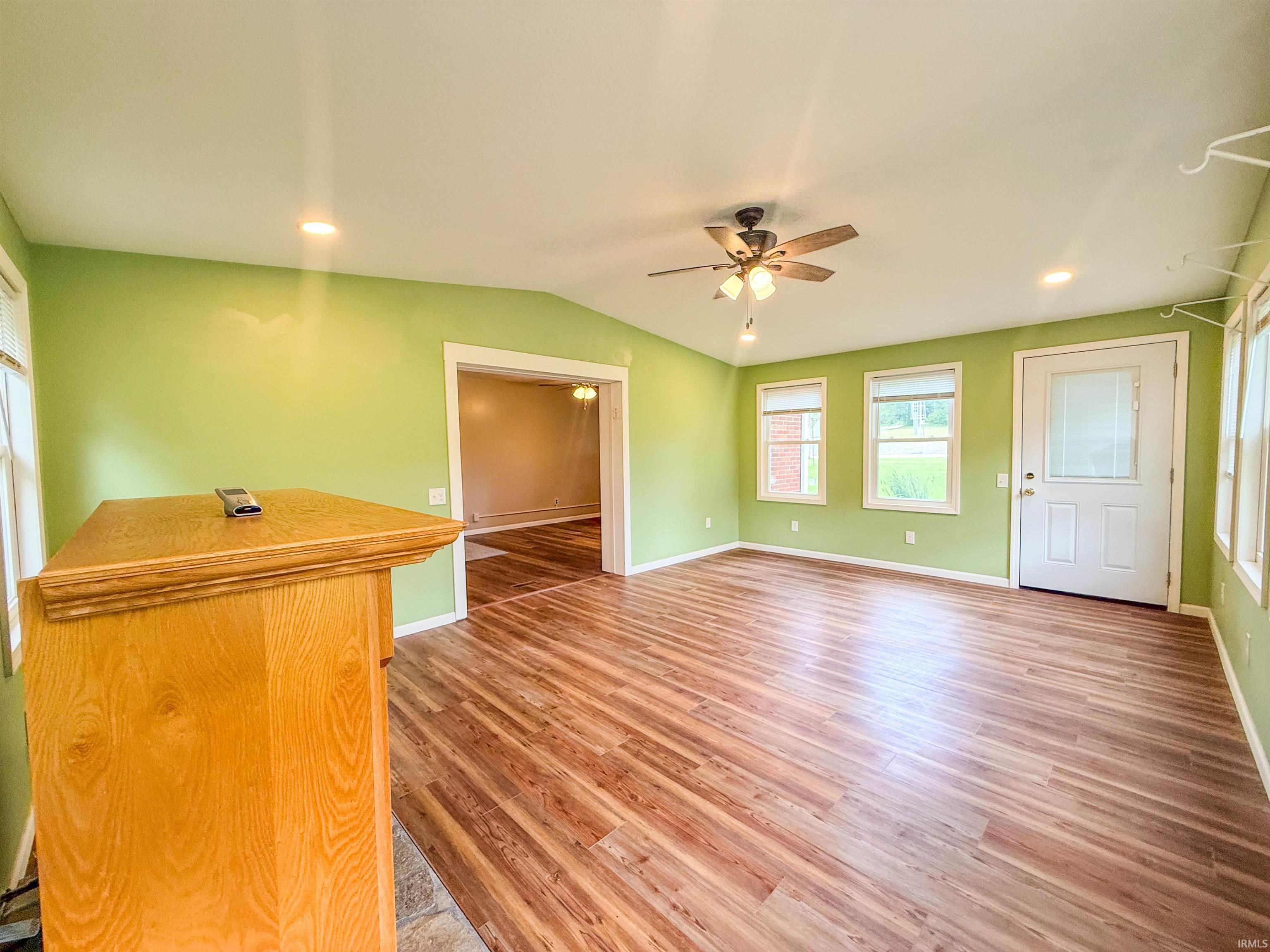Spacious room featuring wood-finish flooring, recessed lighting, and a ceiling fan with light fixture