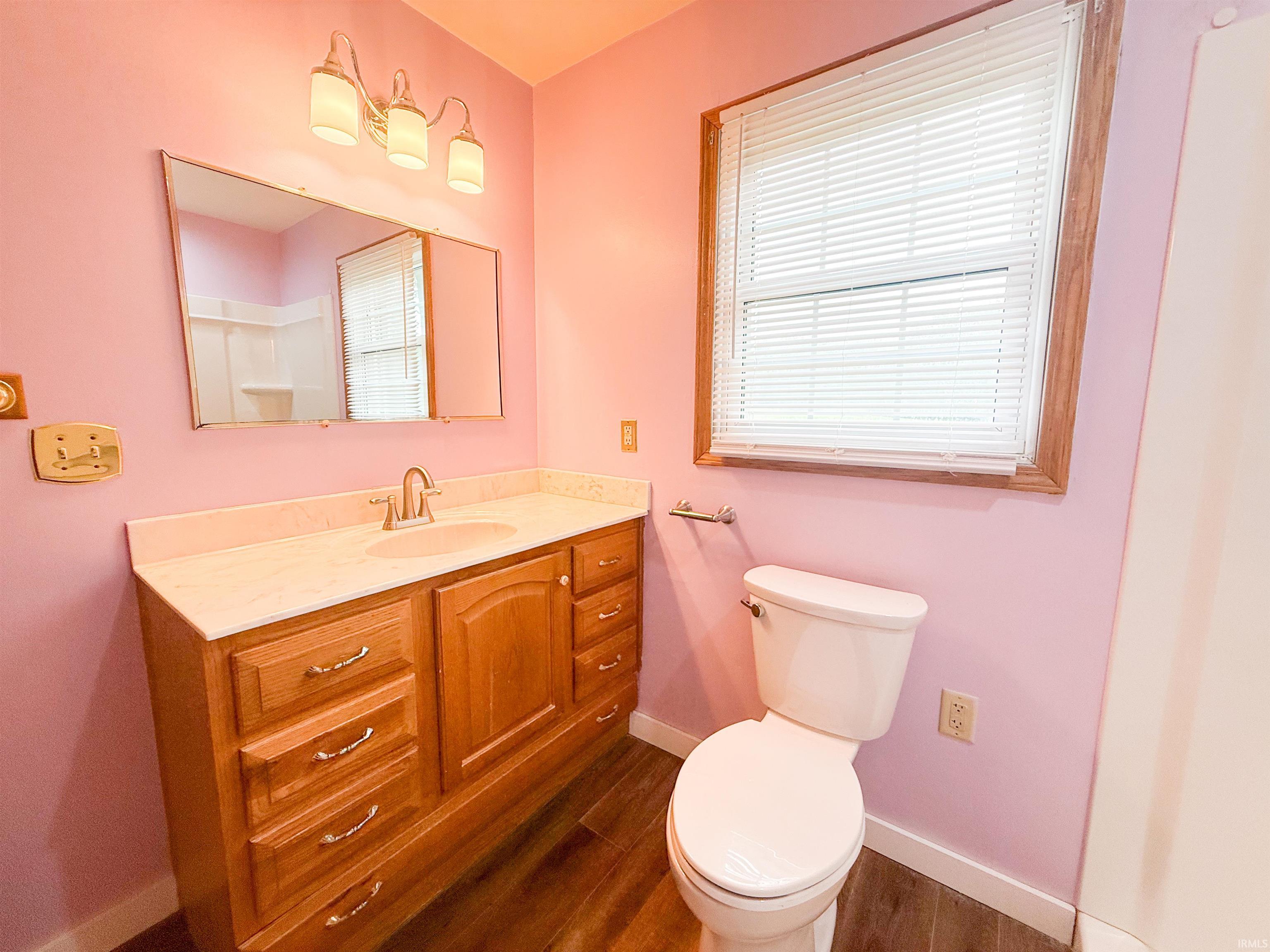 Bathroom featuring a single vanity with wood-finish cabinetry, a light-toned countertop, and a chrome faucet