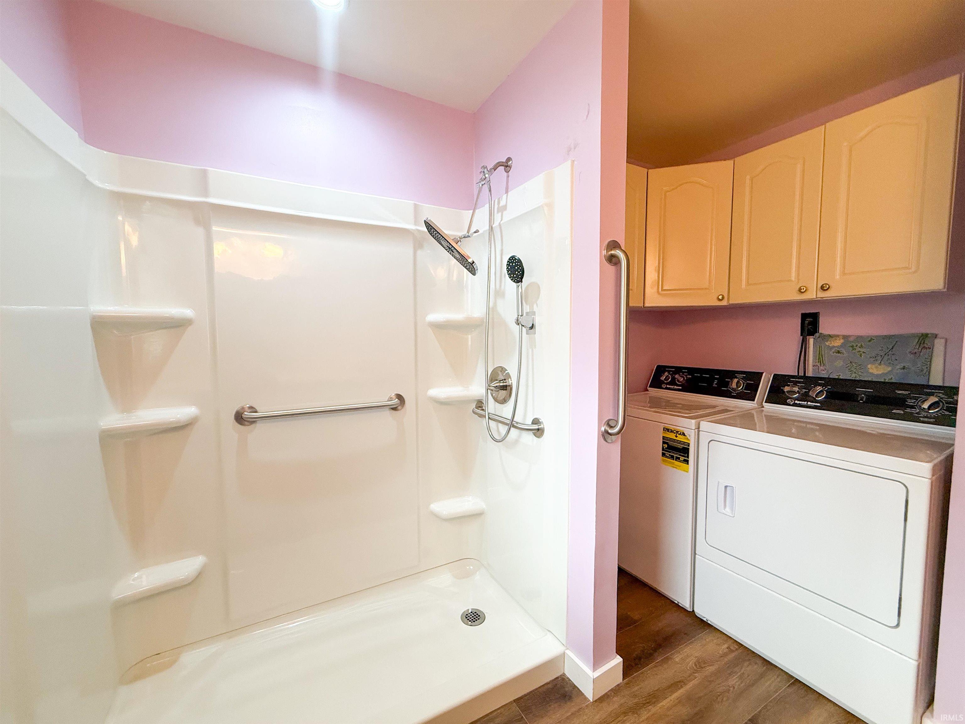 Shower stall with integrated shelving, brushed nickel fixtures, and safety grab bars