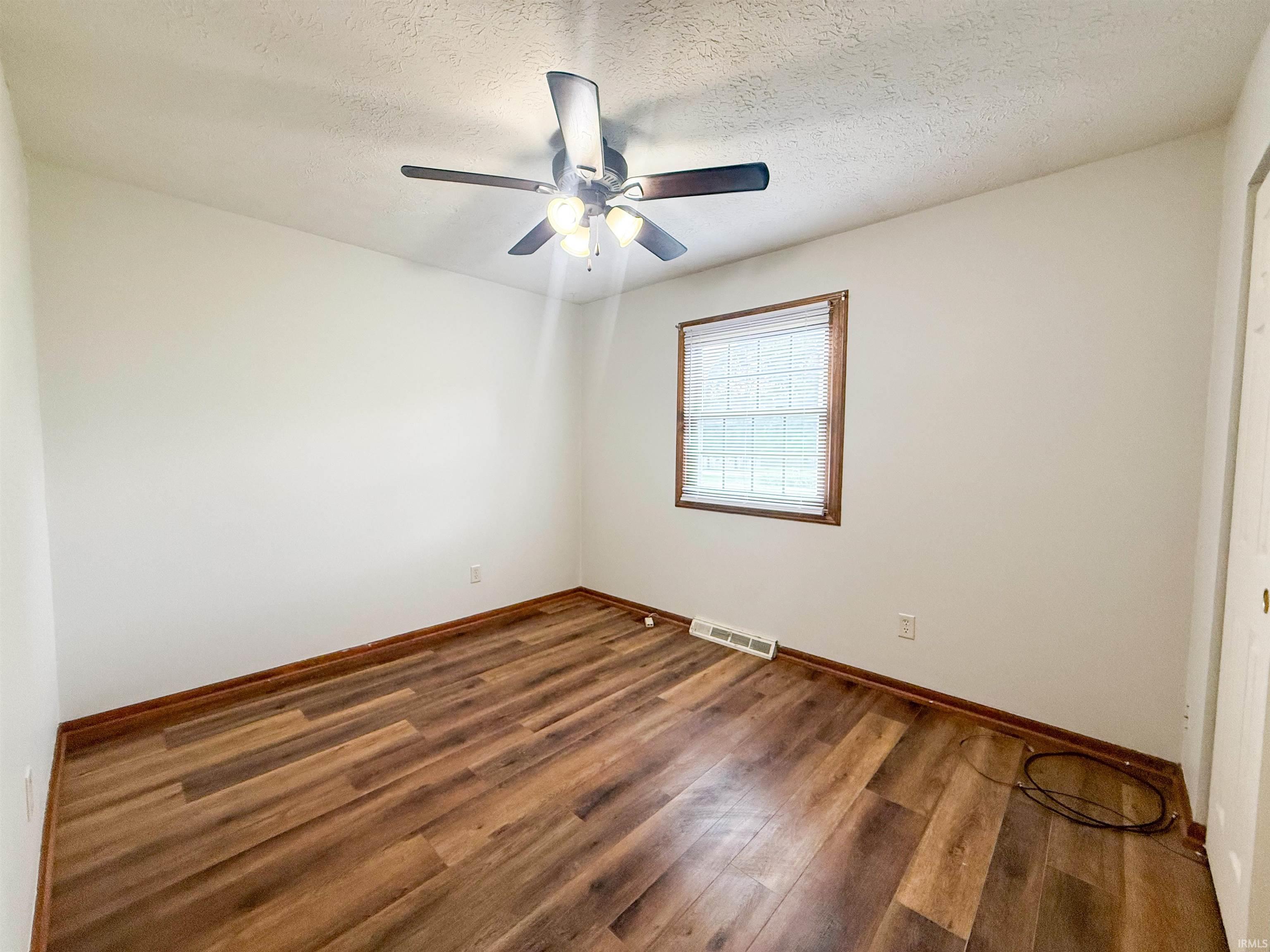 Bright interior space featuring wood-finish flooring, white walls, and a ceiling fan with integrated lighting