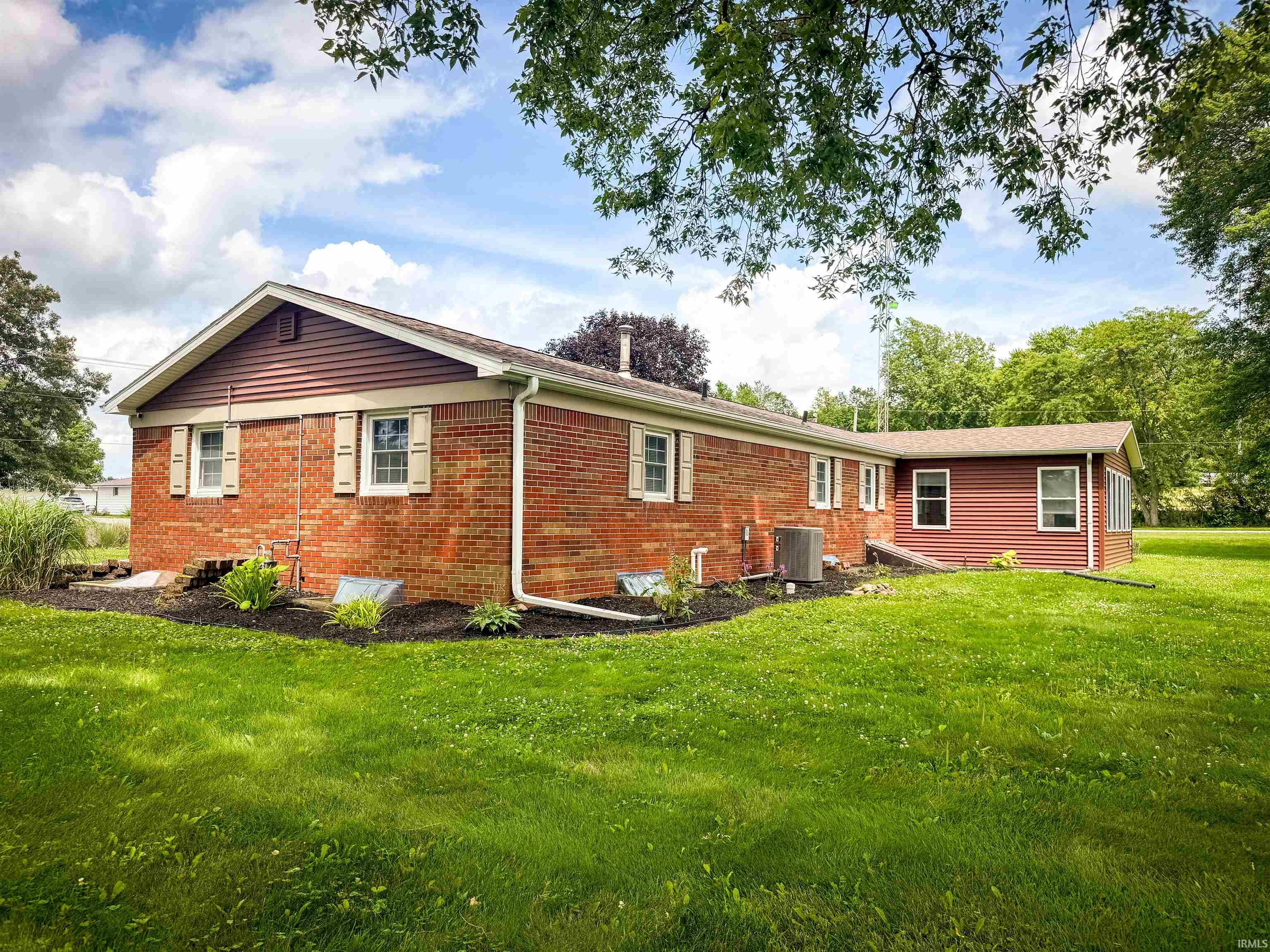 Brick and siding exterior with white window frames and beige shutters