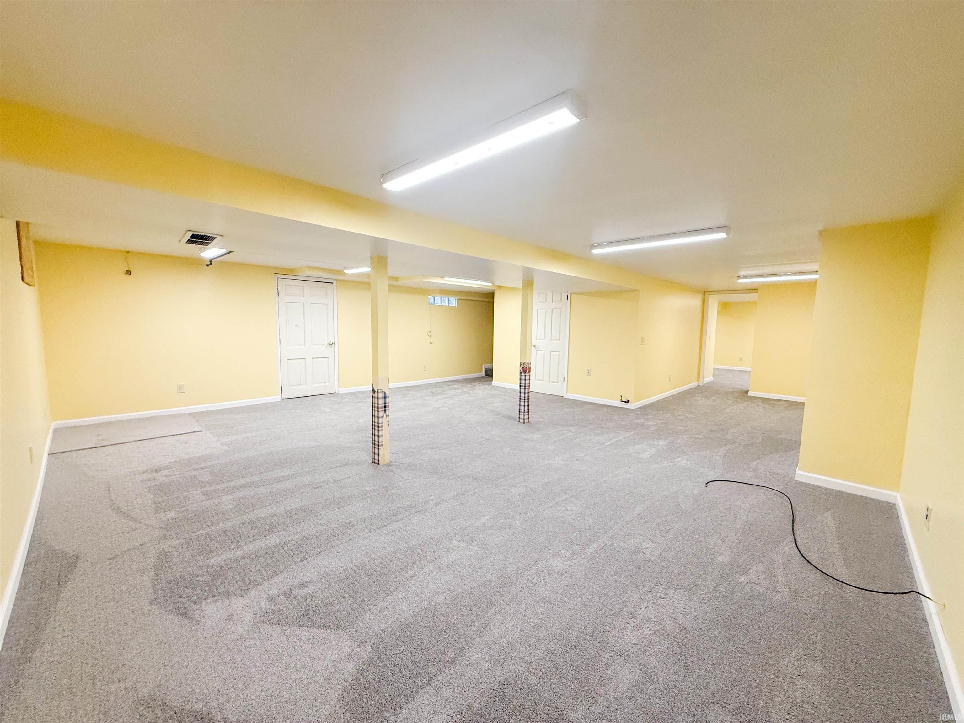 Spacious lower level featuring light gray carpeting, neutral yellow walls, and recessed lighting