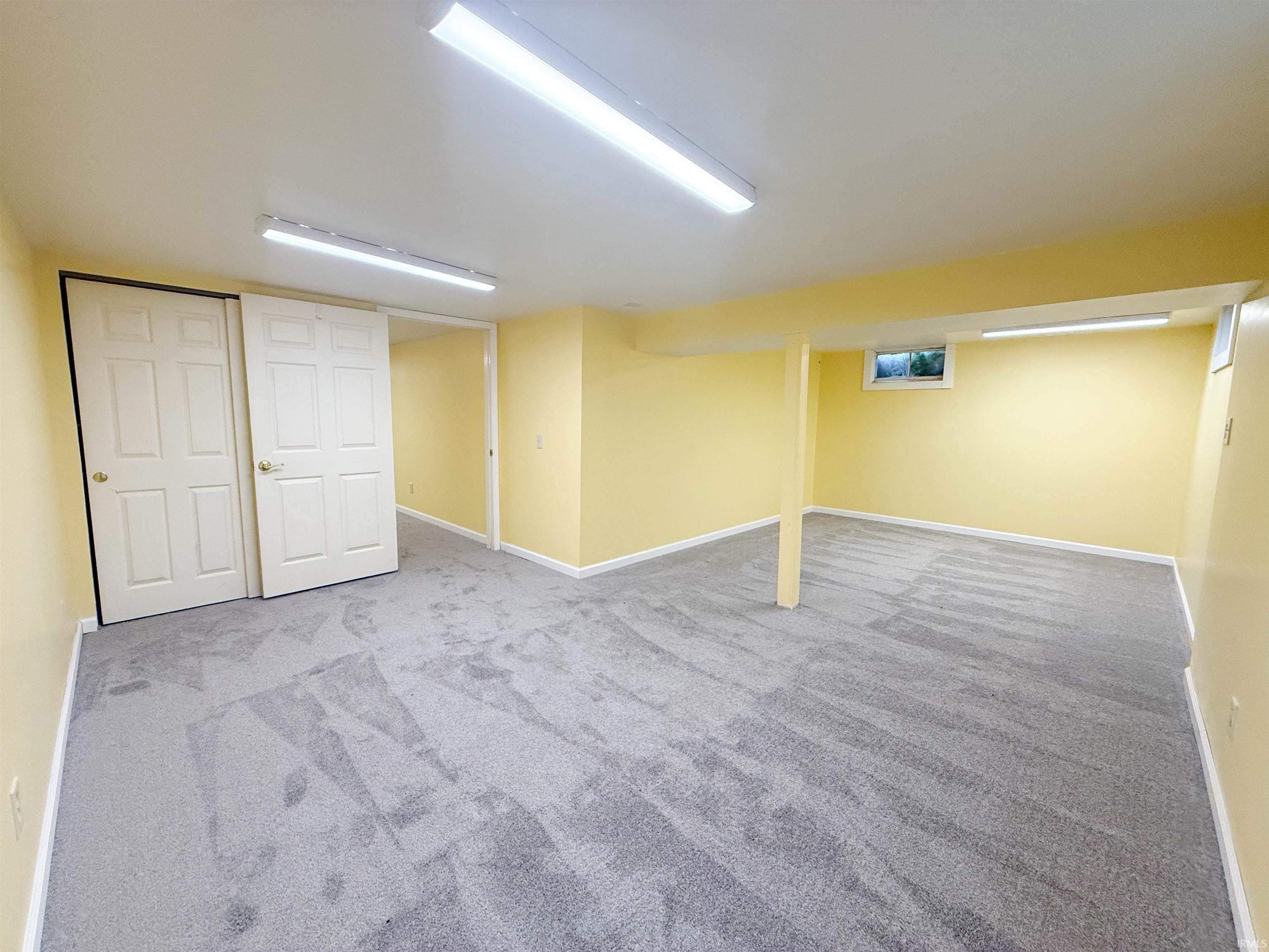 Spacious finished room featuring light yellow walls and new gray patterned carpeting