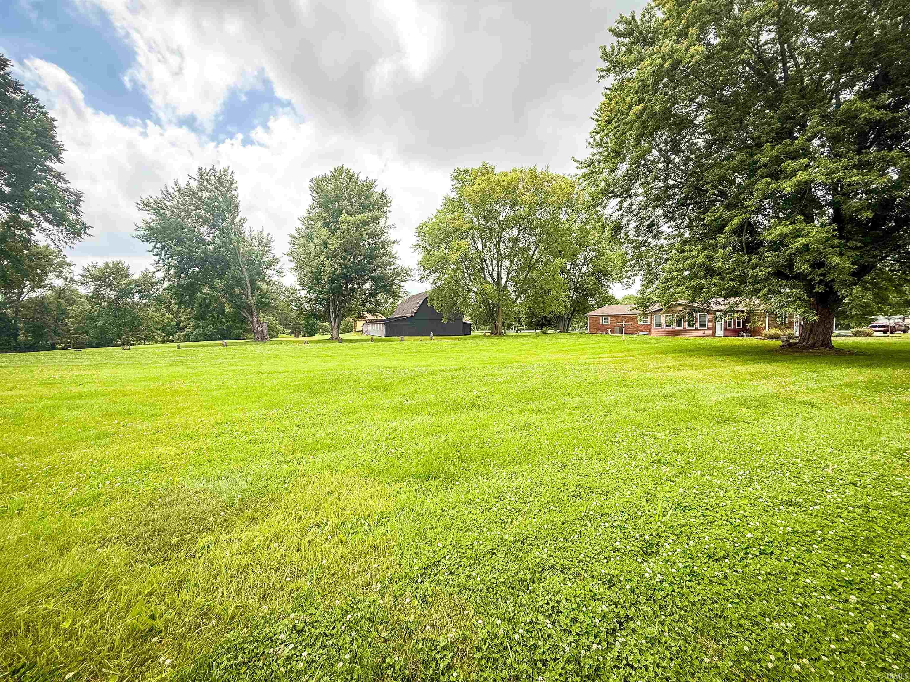 Expansive green lawn with mature trees and a brick residential structure