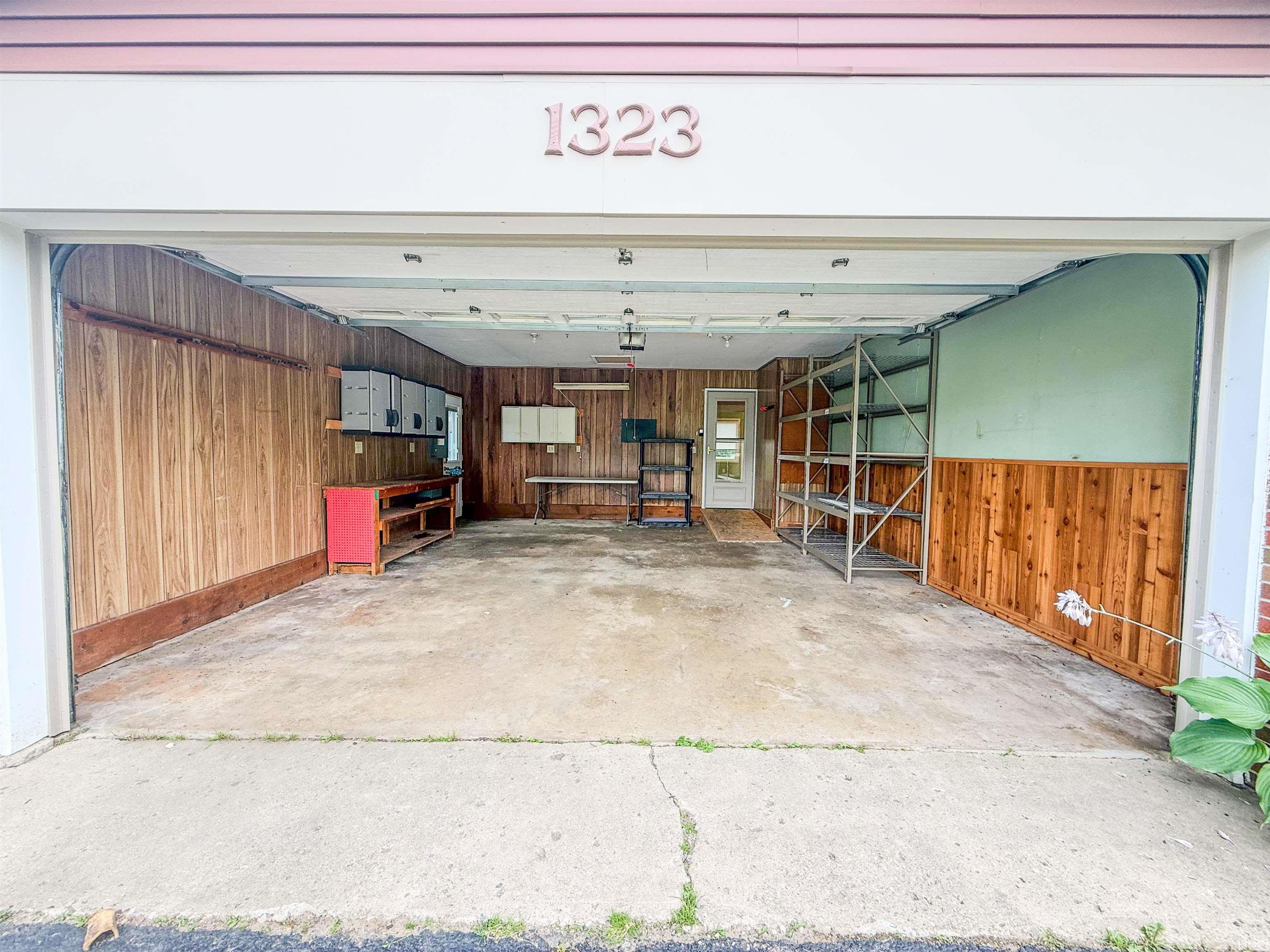 Two-car garage featuring a concrete floor, wood-paneled walls, and built-in cabinetry