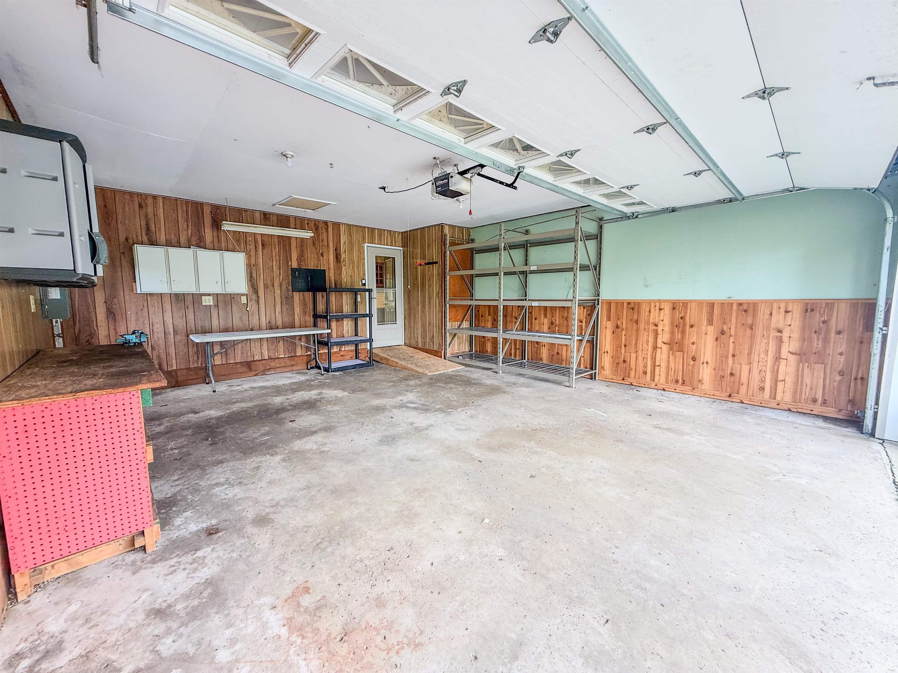 Two-car garage featuring a concrete floor, wood paneling, and an overhead door