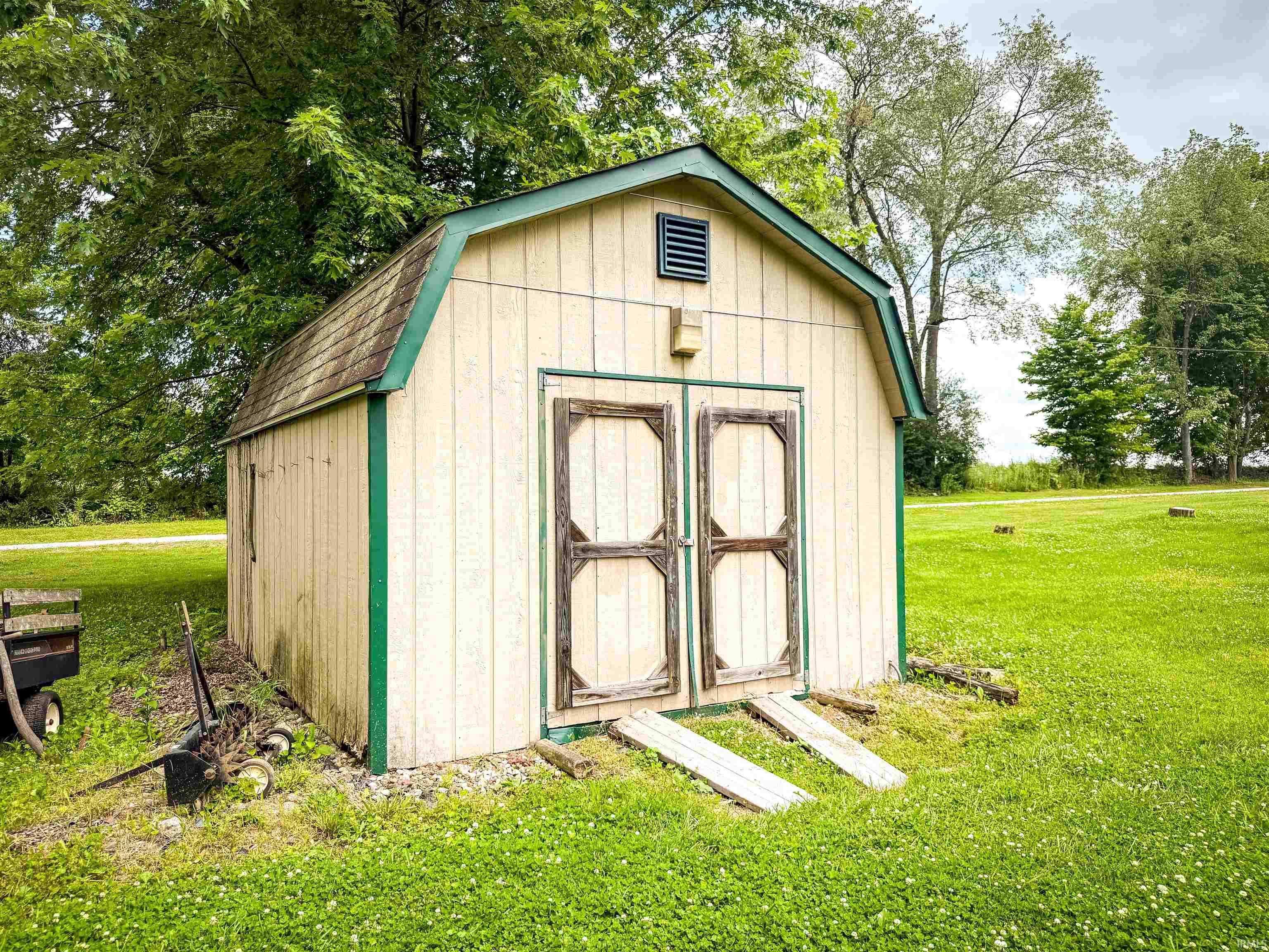 Detached storage shed featuring a gambrel roof and double doors with wooden ramps