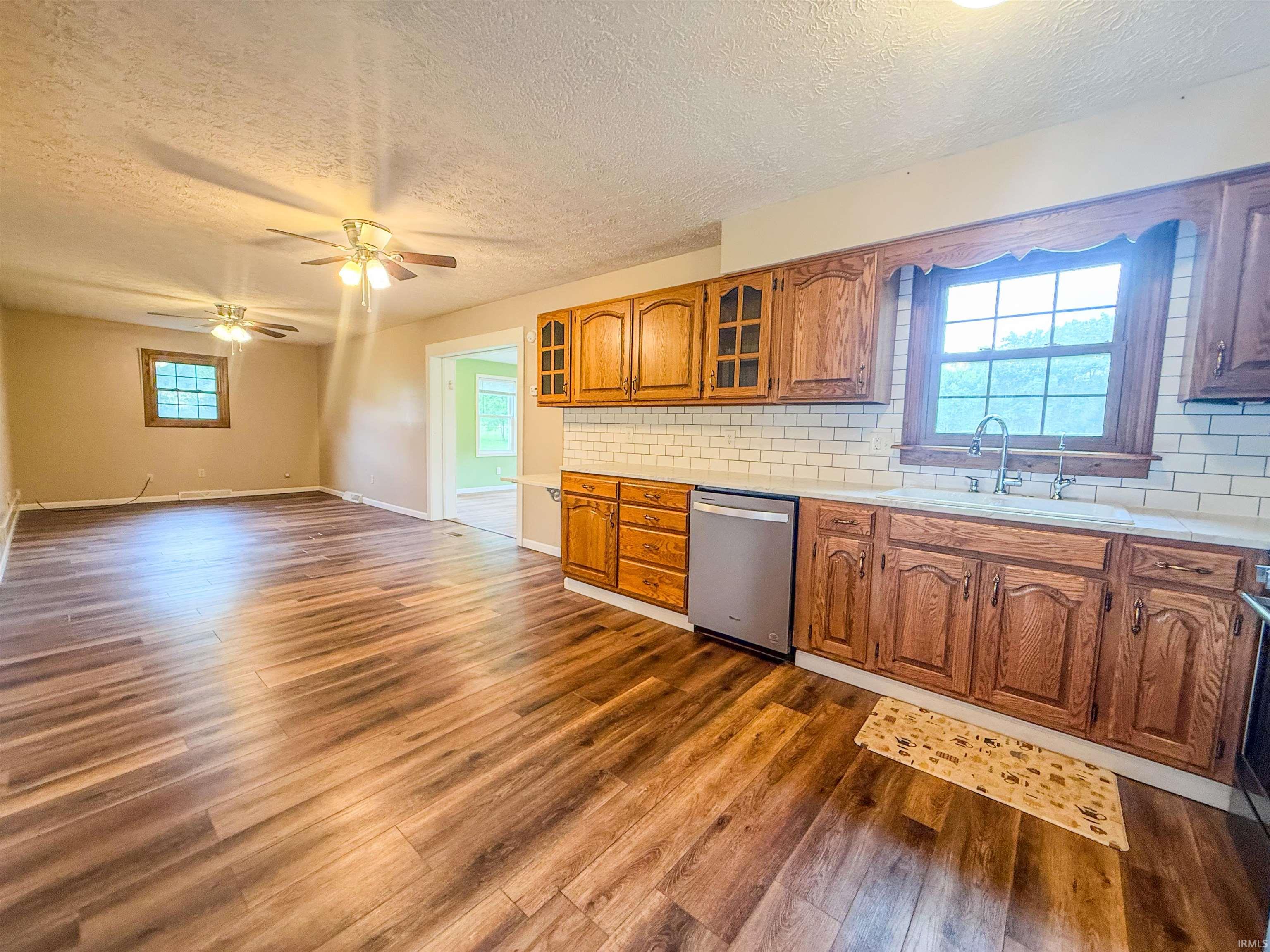 Kitchen featuring wood cabinetry, white subway tile backsplash, and a stainless steel dishwasher