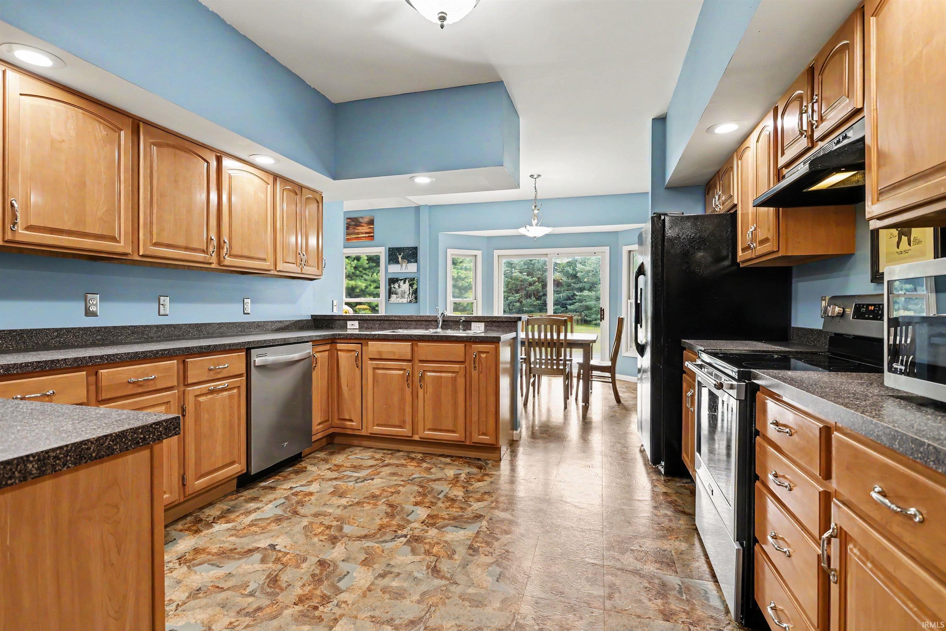 Kitchen featuring extensive wood cabinetry, dark speckled countertops, and patterned floor tiling