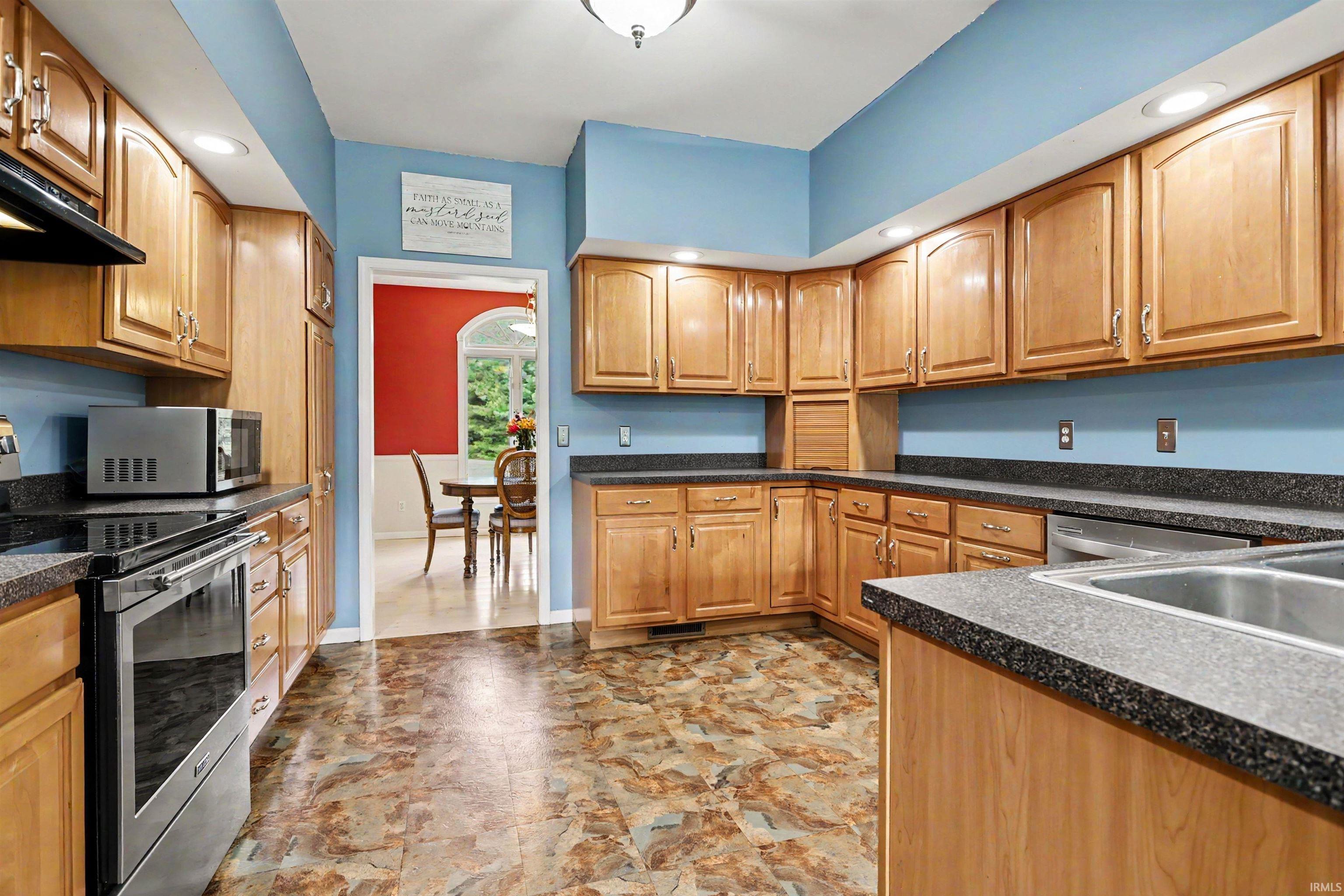 Kitchen featuring abundant wood cabinetry, dark speckled countertops, stainless steel sink, and recessed lighting