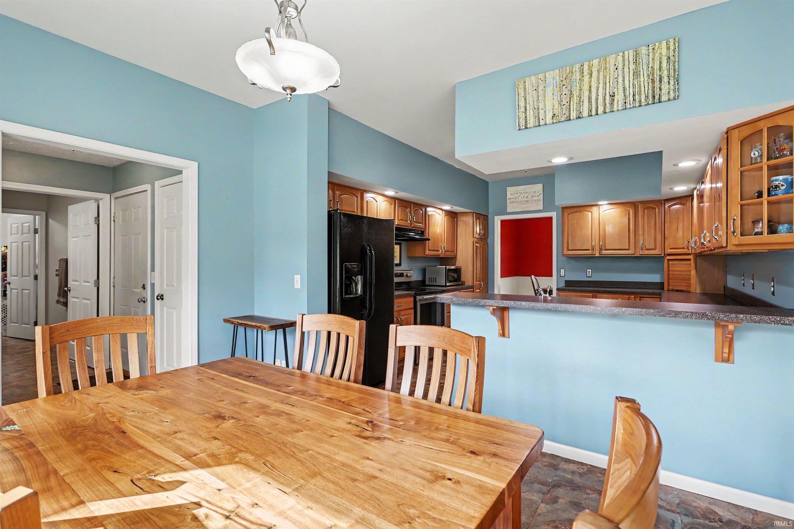 Open-concept kitchen and dining area featuring warm wood cabinetry and a breakfast bar