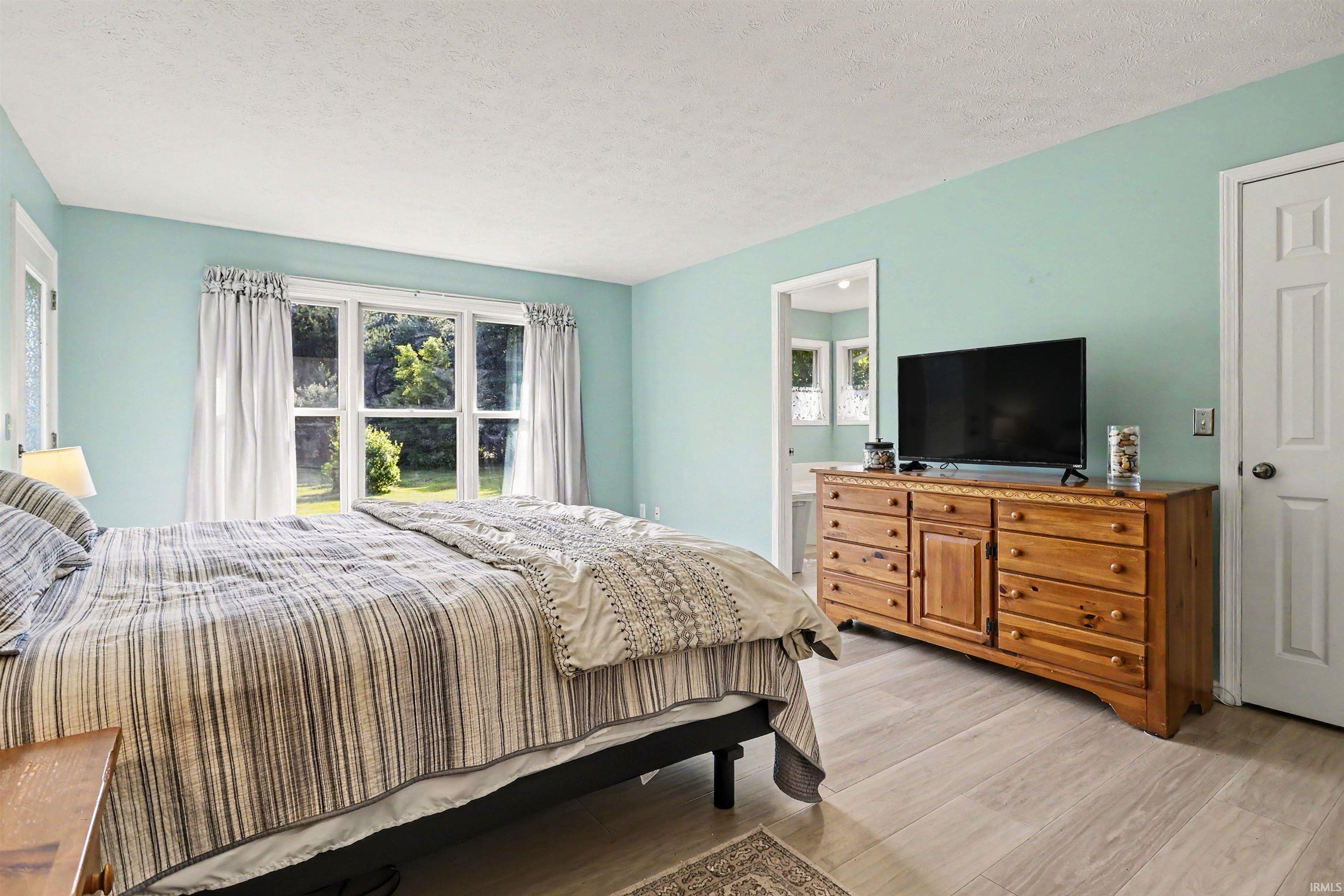Bright room featuring a large multi-pane window, wood-finish flooring, and a six-panel interior door