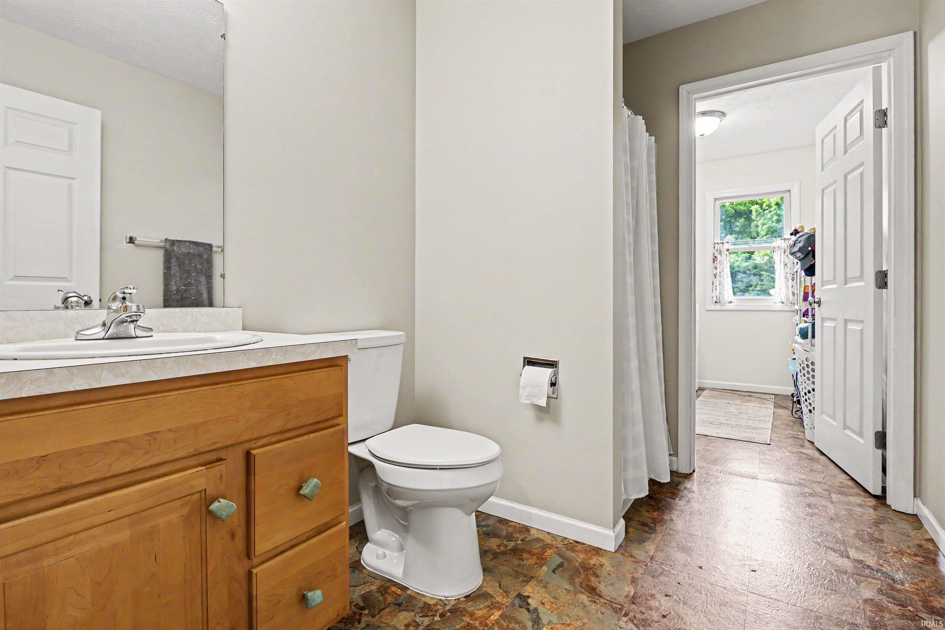 Bathroom featuring a wood-finish vanity with a laminate countertop and an integrated sink basin