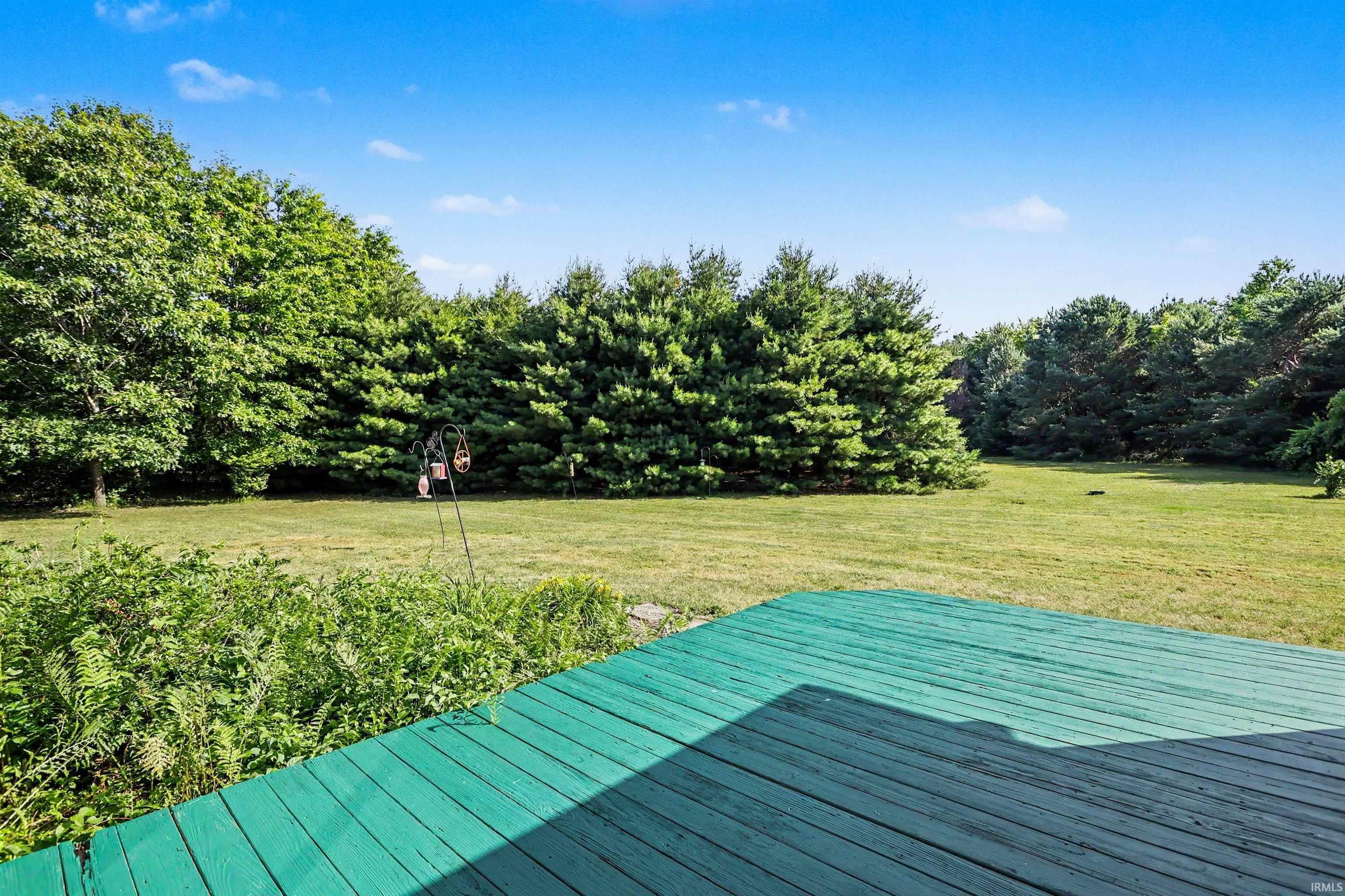 Expansive green-stained wood deck overlooking a substantial grassy yard