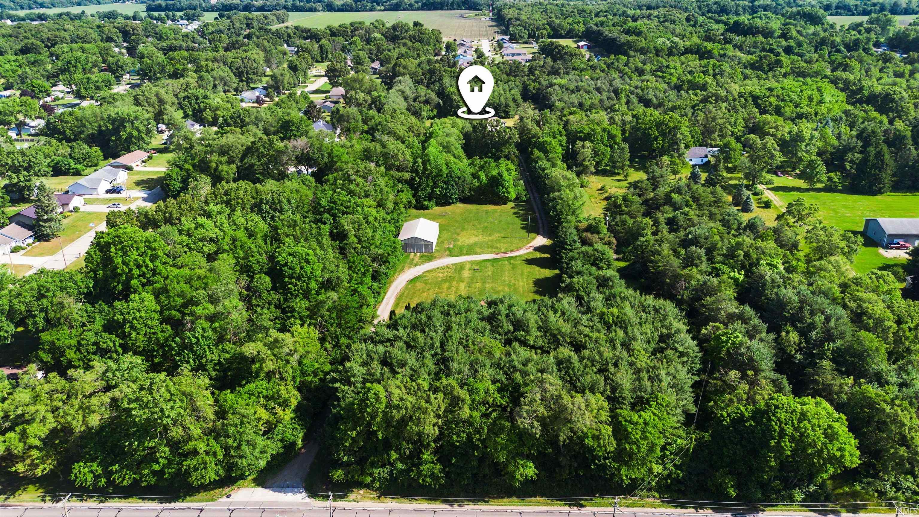 Expansive wooded lot featuring a detached structure, a curved driveway, and ample green space