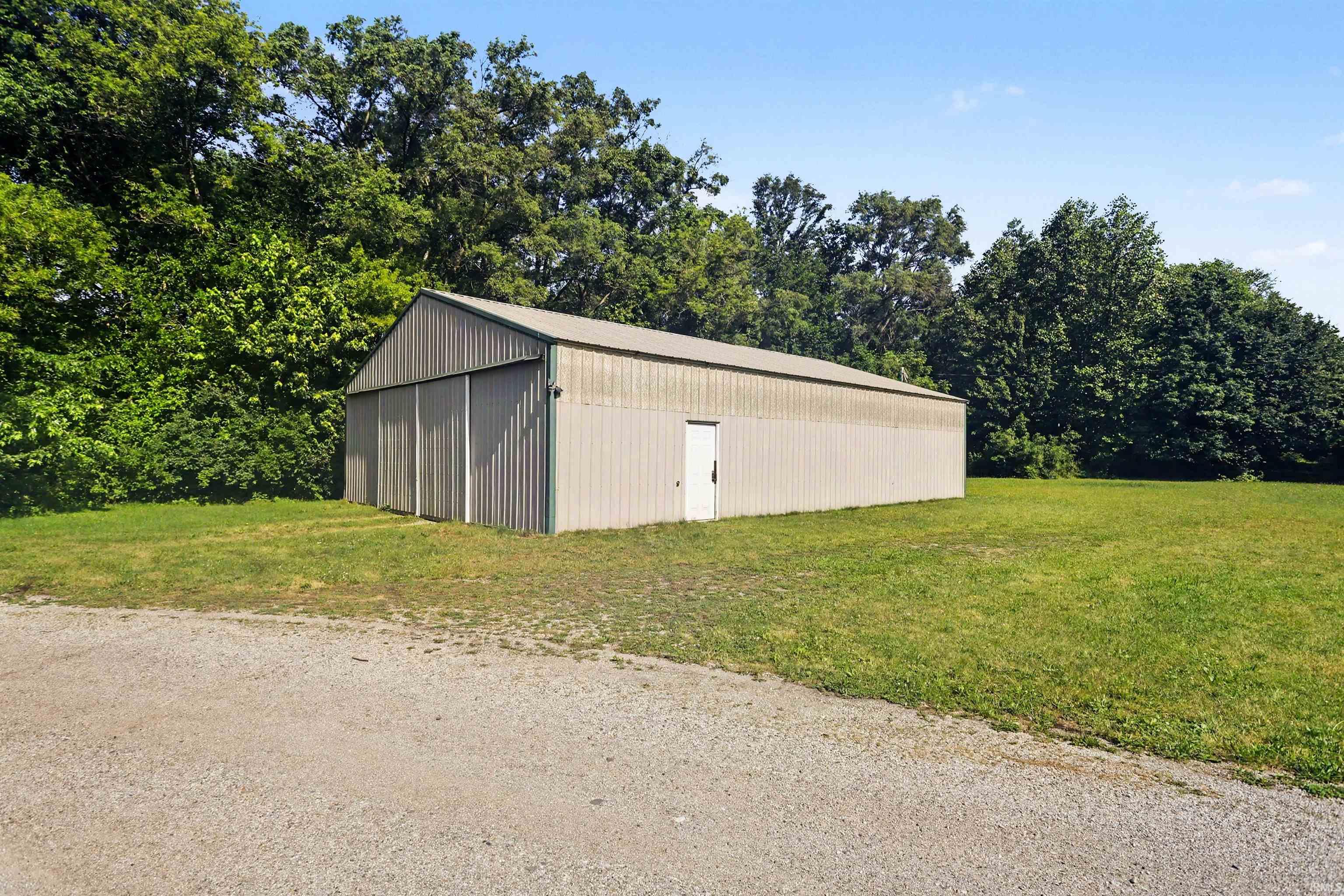 Large metal outbuilding with a gable roof, featuring a single entry door and two large sliding doors