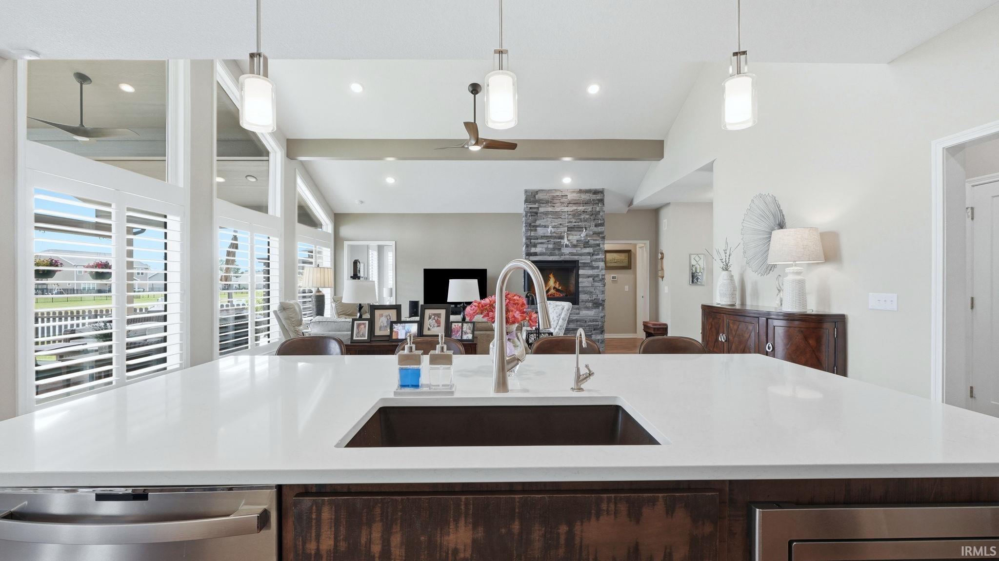 Kitchen island featuring a single basin sink and a high-arc faucet, with white countertops and dark wood-finish cabinetry
