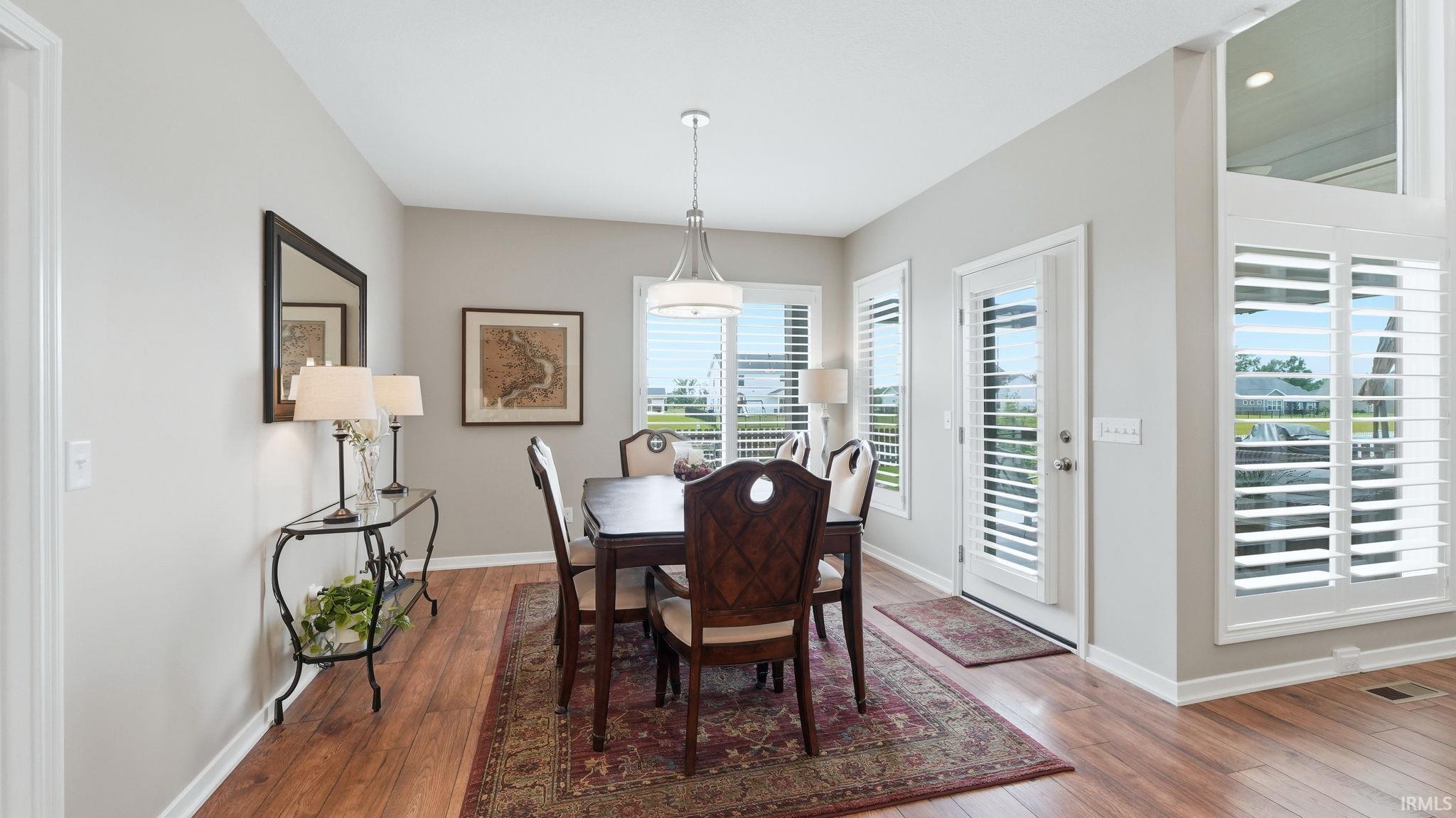 Dining space with wood-finish flooring, light grey walls, and a contemporary chandelier
