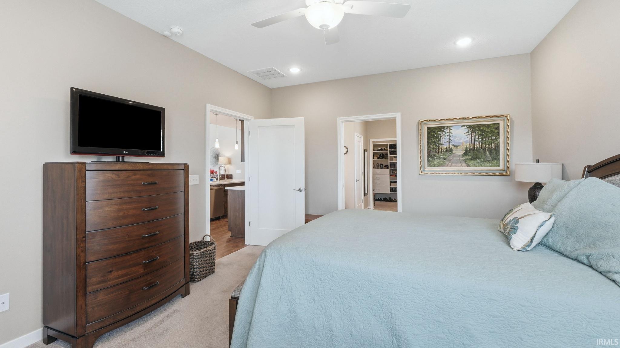 Spacious bedroom featuring light neutral wall tones, recessed lighting, and a ceiling fan