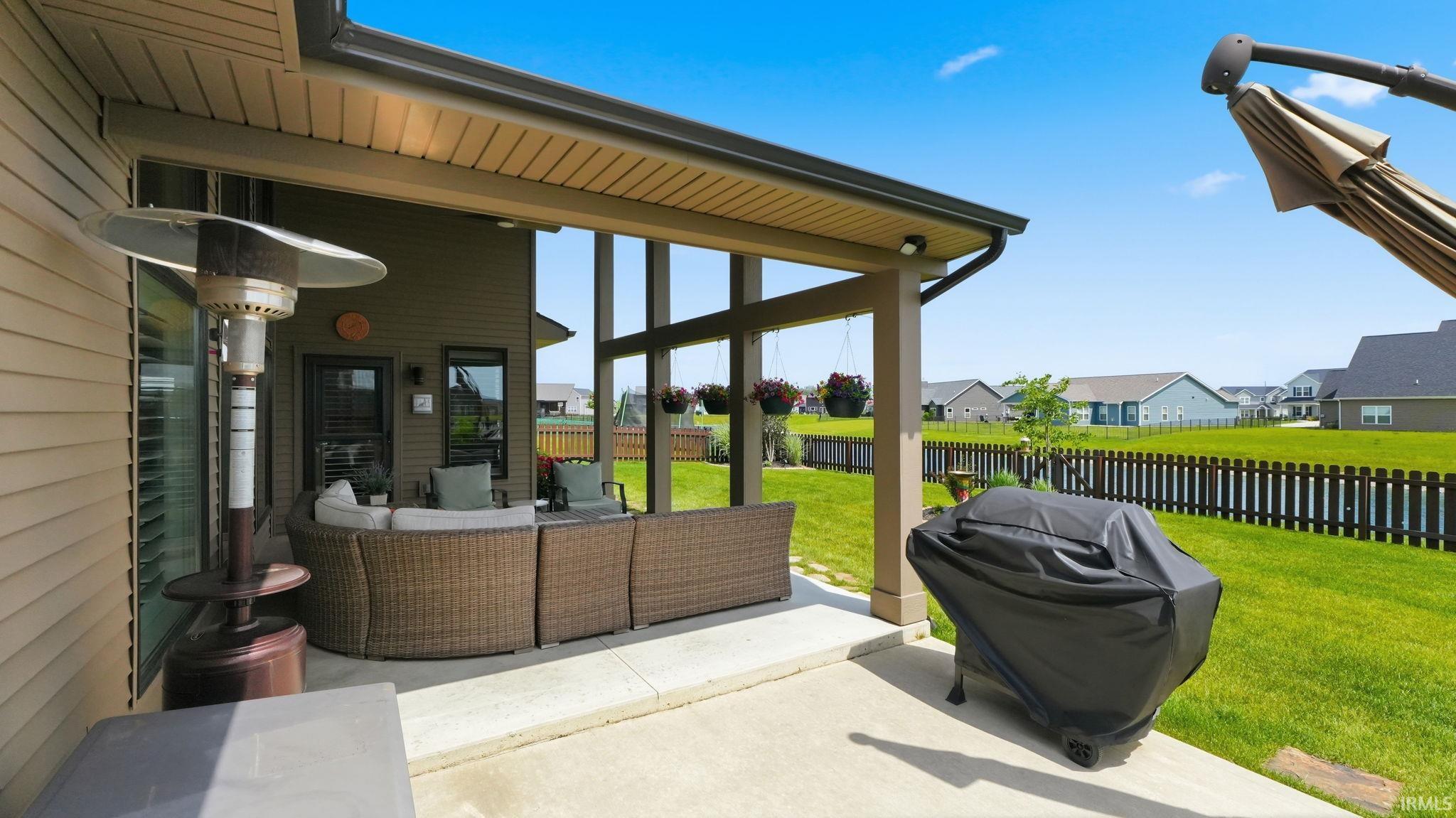 Expansive concrete patio featuring a covered outdoor living area and a spacious, flat lawn