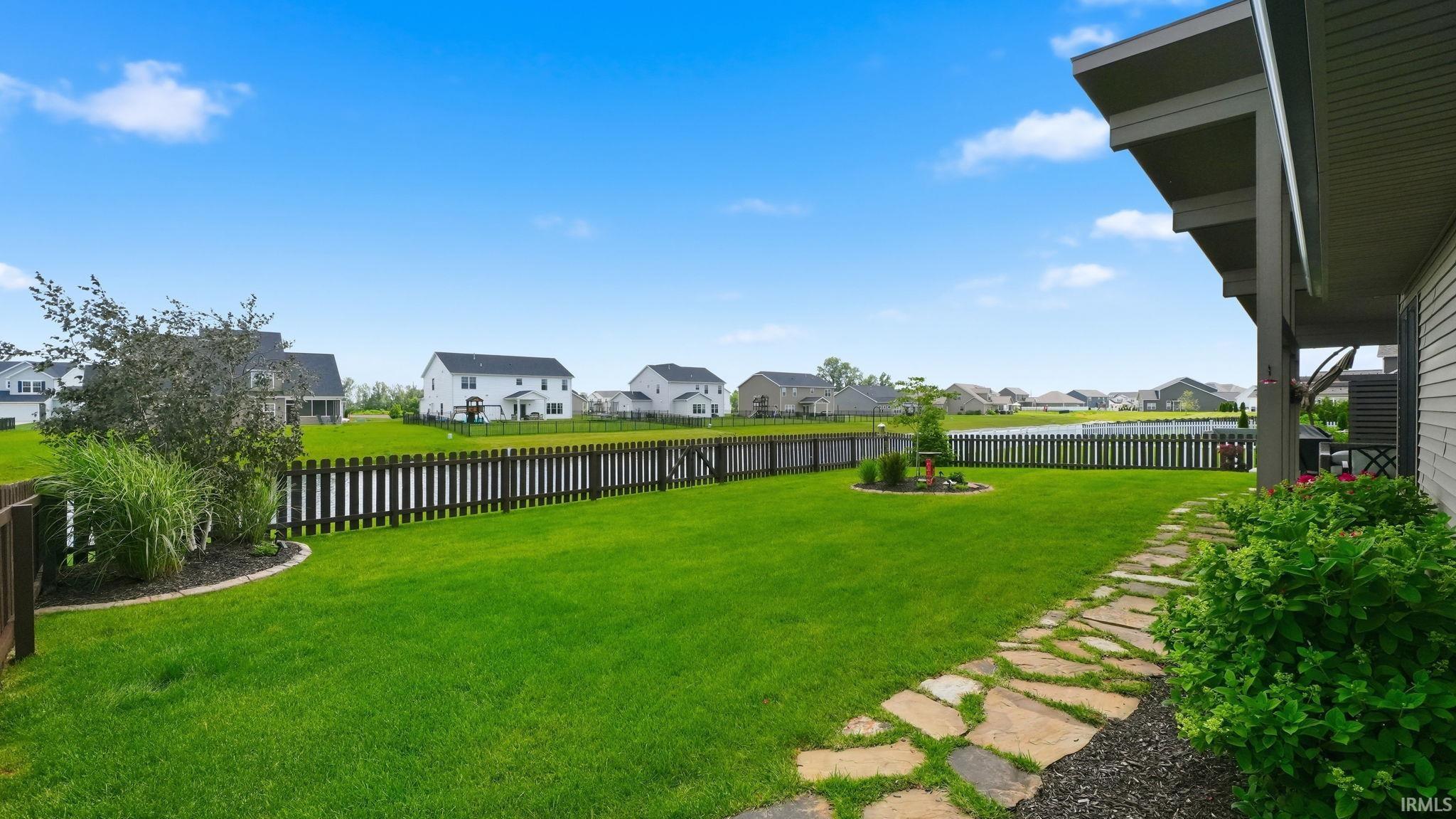 Expansive backyard featuring a manicured lawn, stone pathway, and mature landscaping