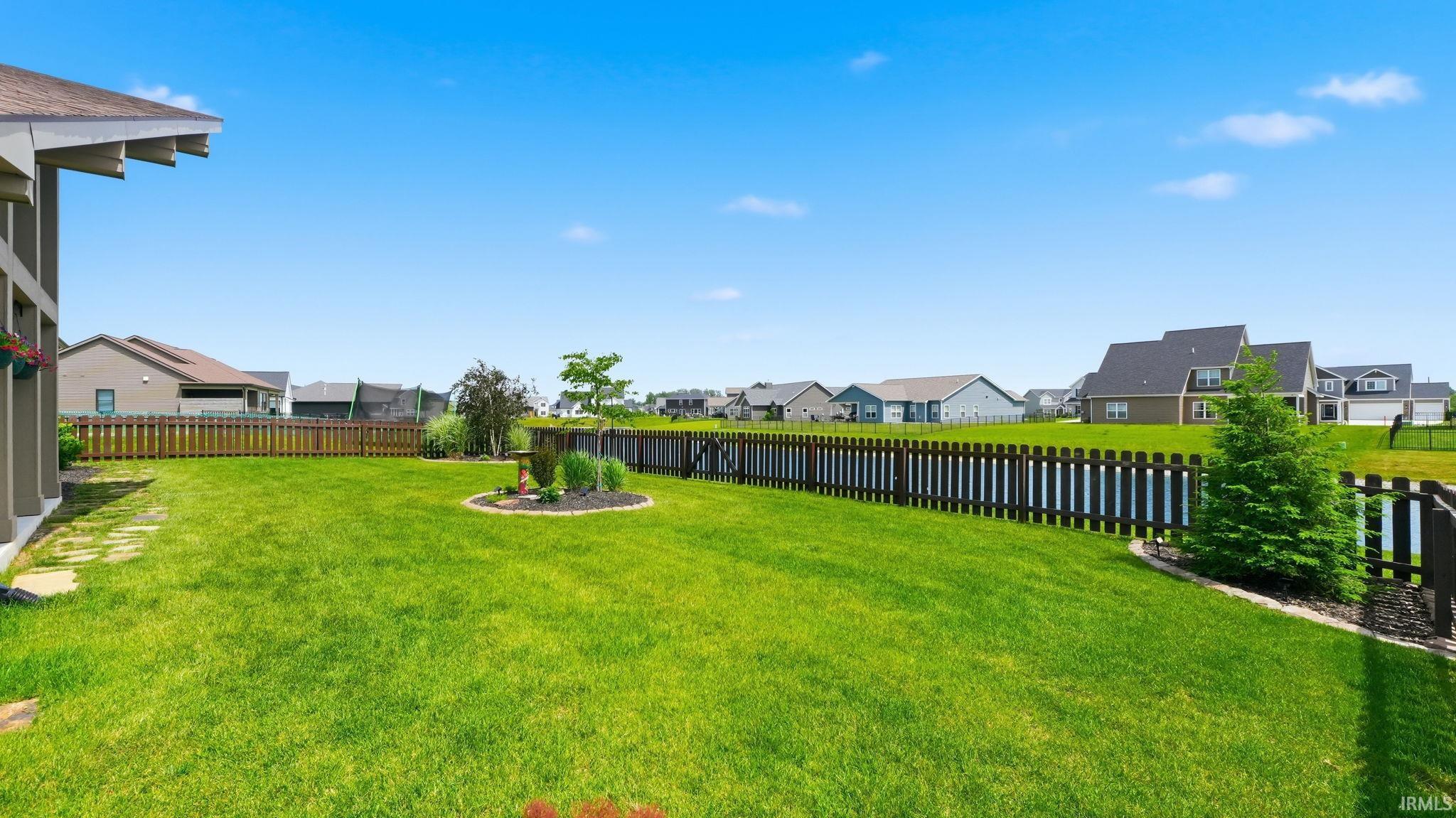 Expansive green lawn defined by a dark-stained wood picket fence