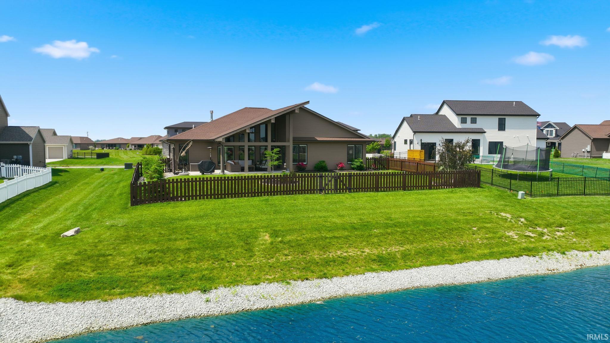 Expansive green lawn bordering a body of water with a gravel edge