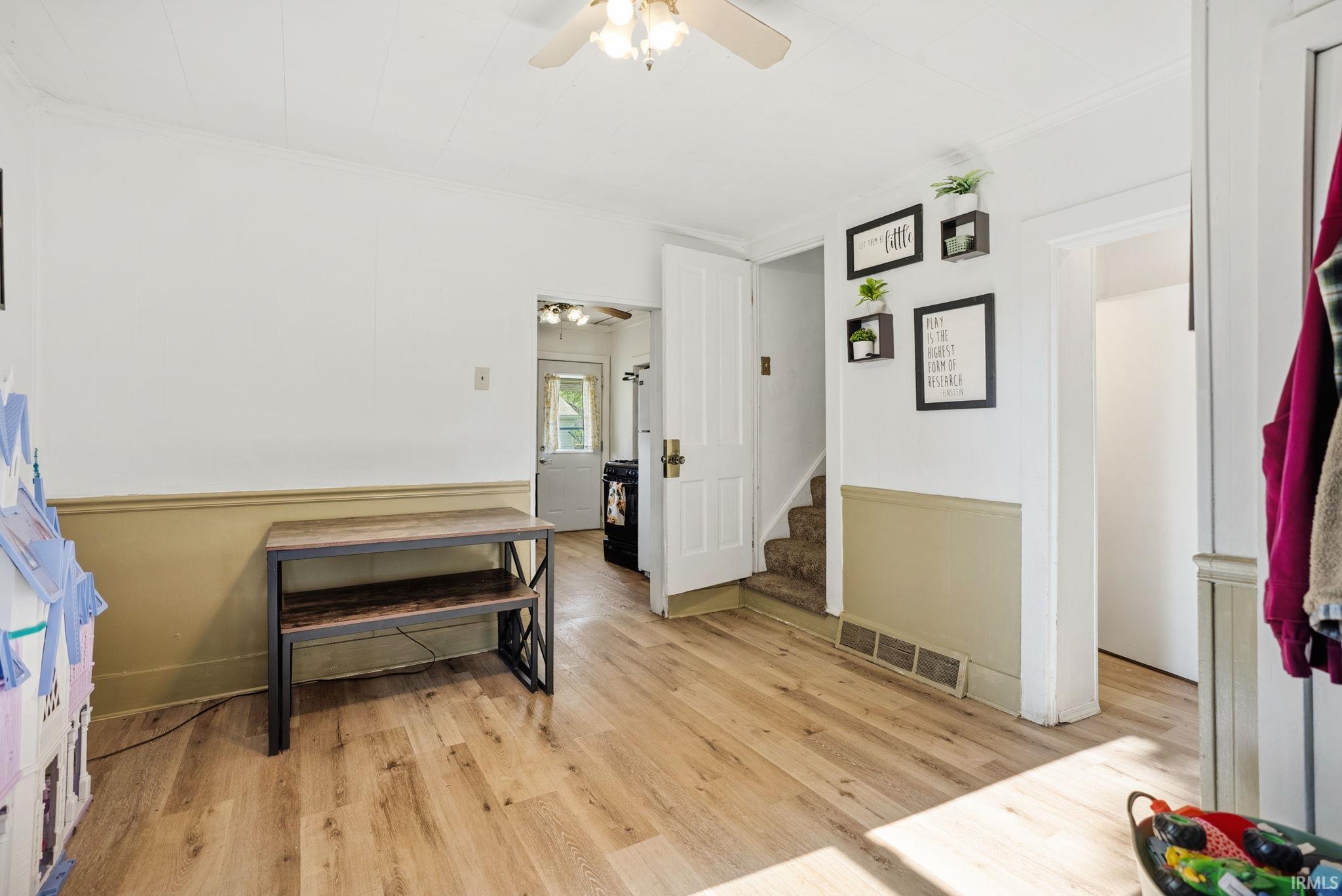 Interior space featuring wood-finish flooring, two-tone wall paint, and a ceiling fan with integrated lighting