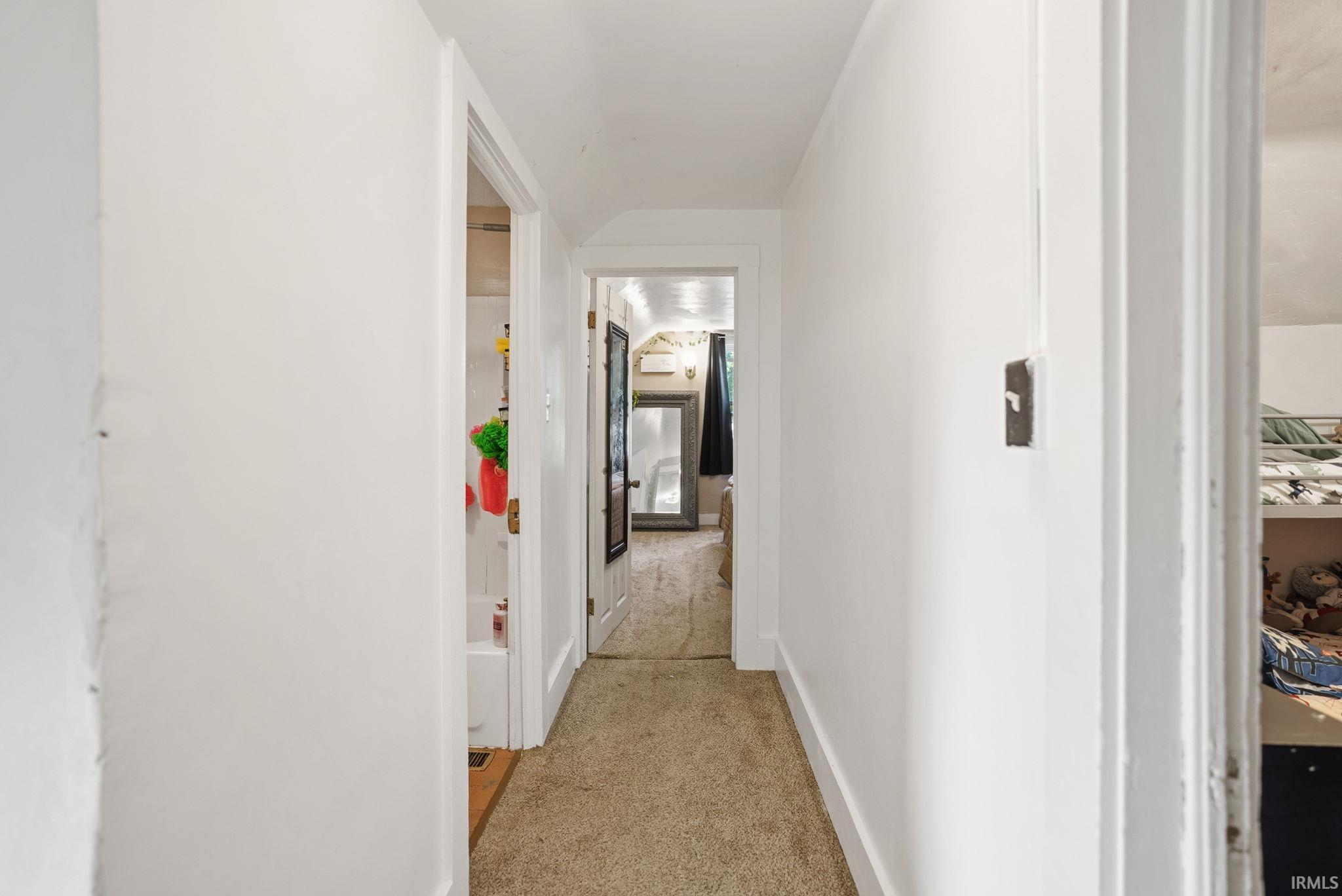 Hallway with light-colored carpeting and white painted walls