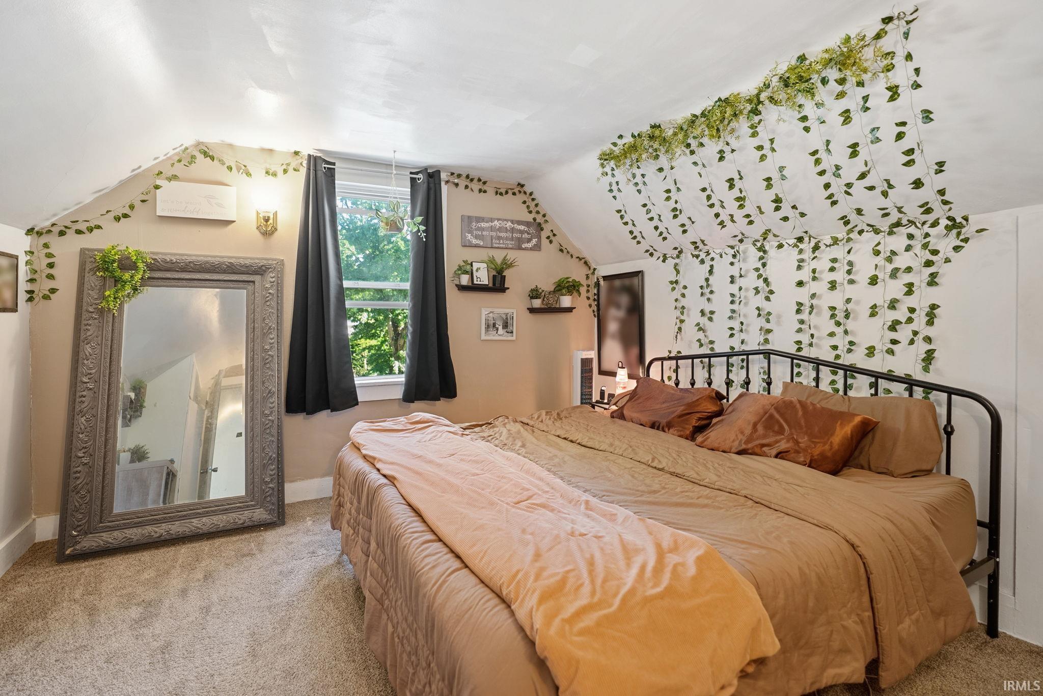 Carpeted room featuring sloped ceilings and a window with dark drapes
