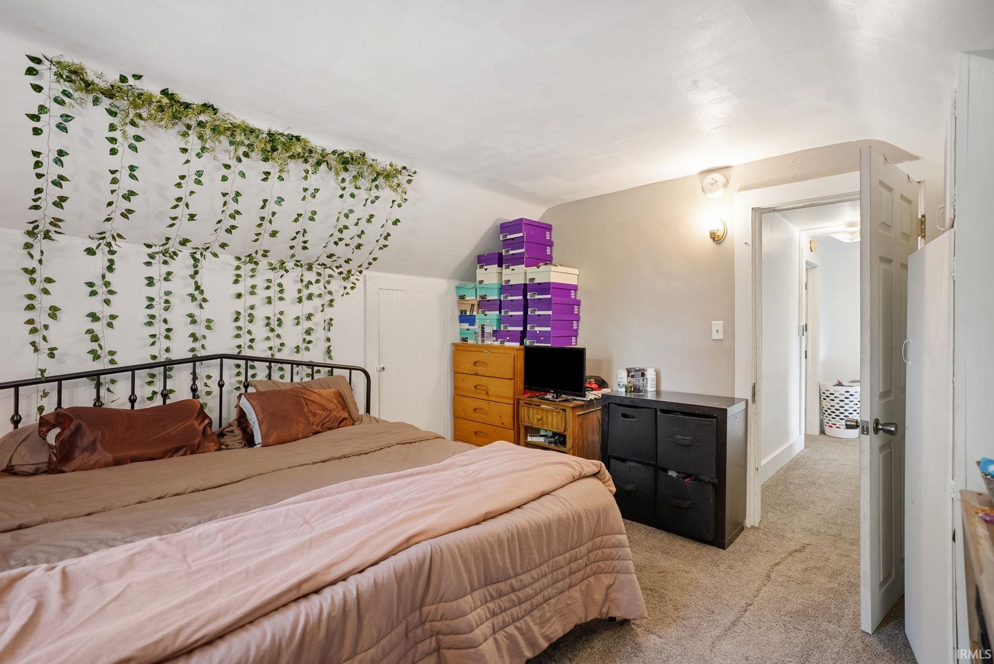 Carpeted room featuring a sloped ceiling, an interior door, and a wall-mounted light fixture