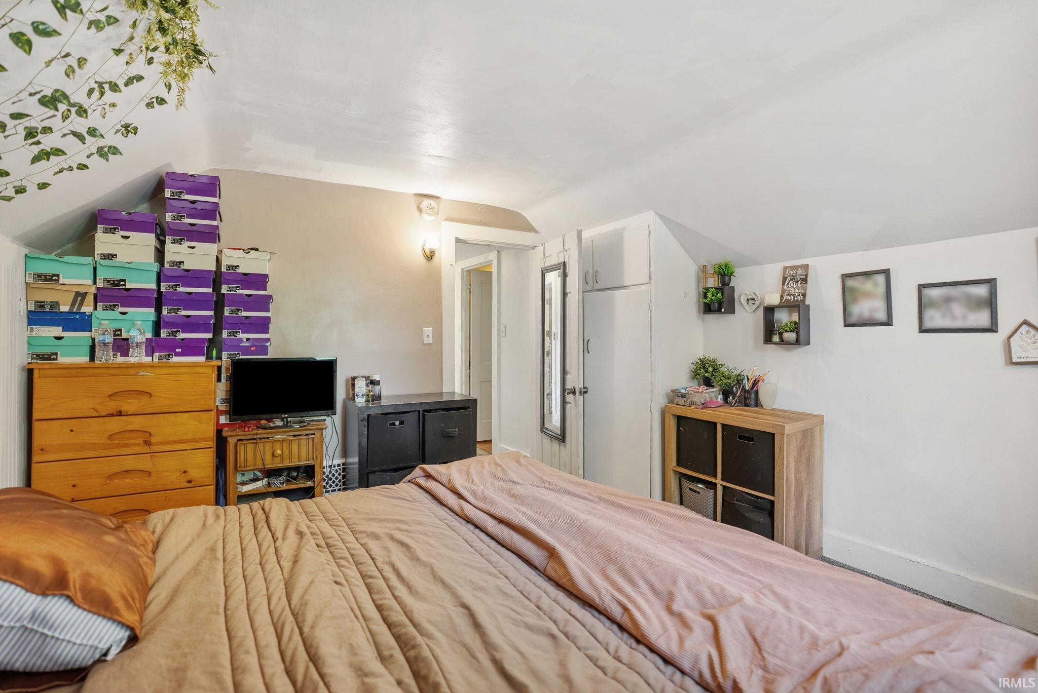 Bedroom featuring sloped ceilings, a wall-mounted light fixture, and white painted walls
