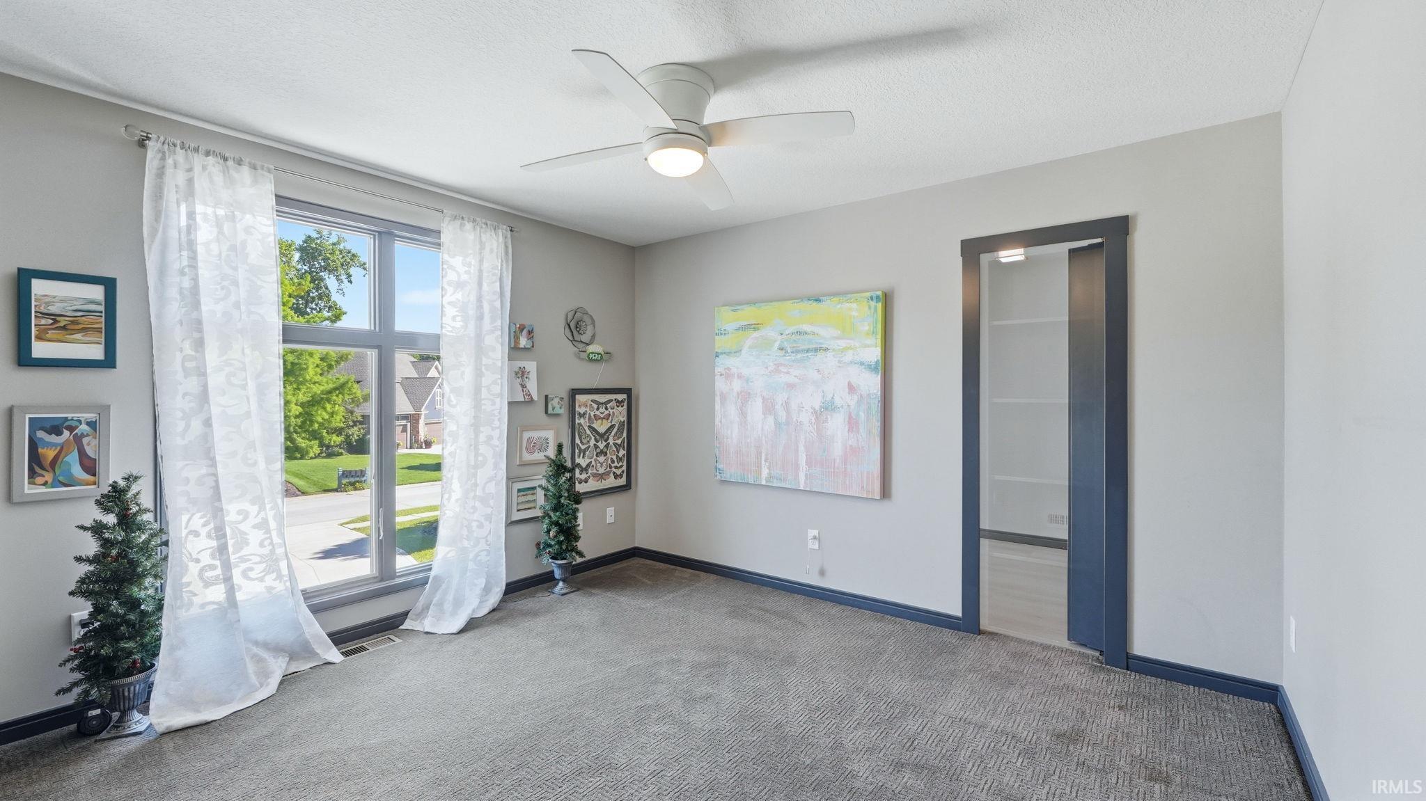 Room with a large picture window, a ceiling fan with integrated lighting, and a built-in display cabinet with glass shelving