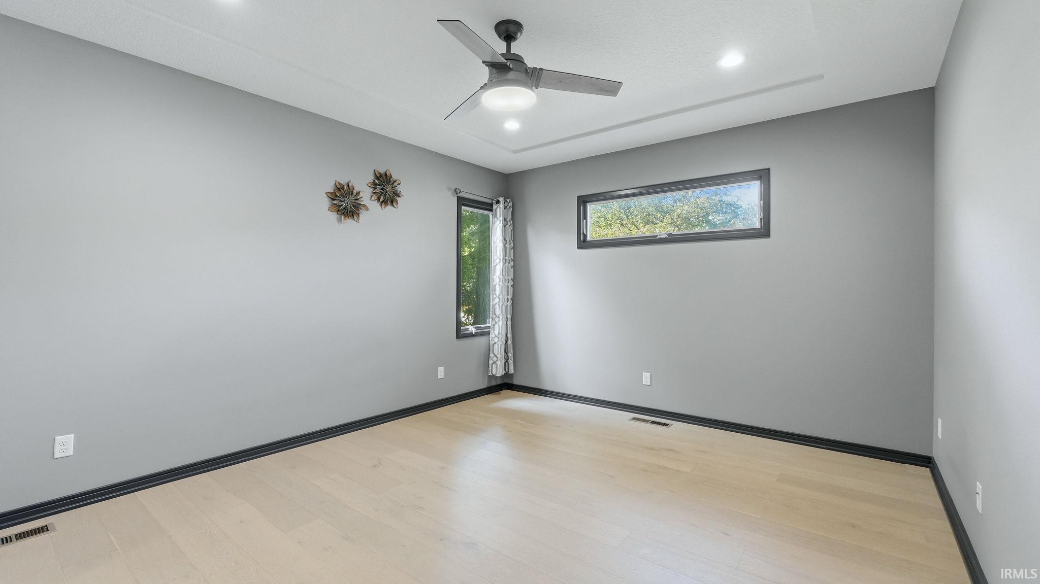 Spacious room featuring light wood-finish flooring and contemporary gray walls