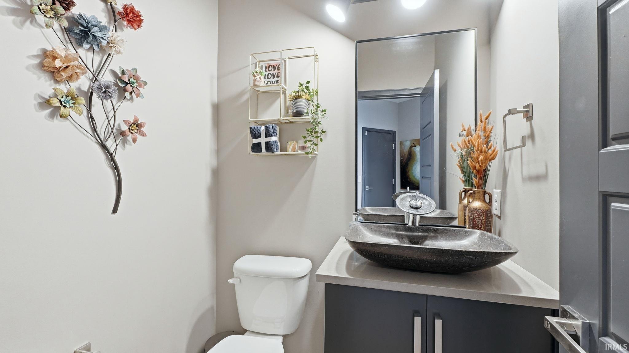 Modern vanity featuring a vessel sink, dark cabinetry, and light countertop