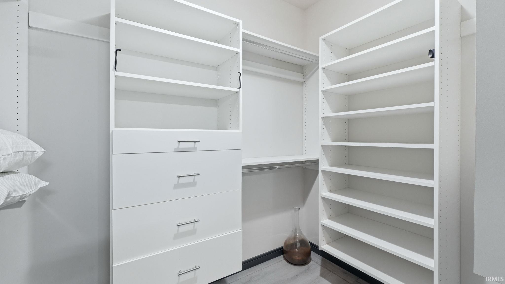 Custom closet system featuring white shelving, four drawers with brushed nickel hardware, and multiple hanging rods