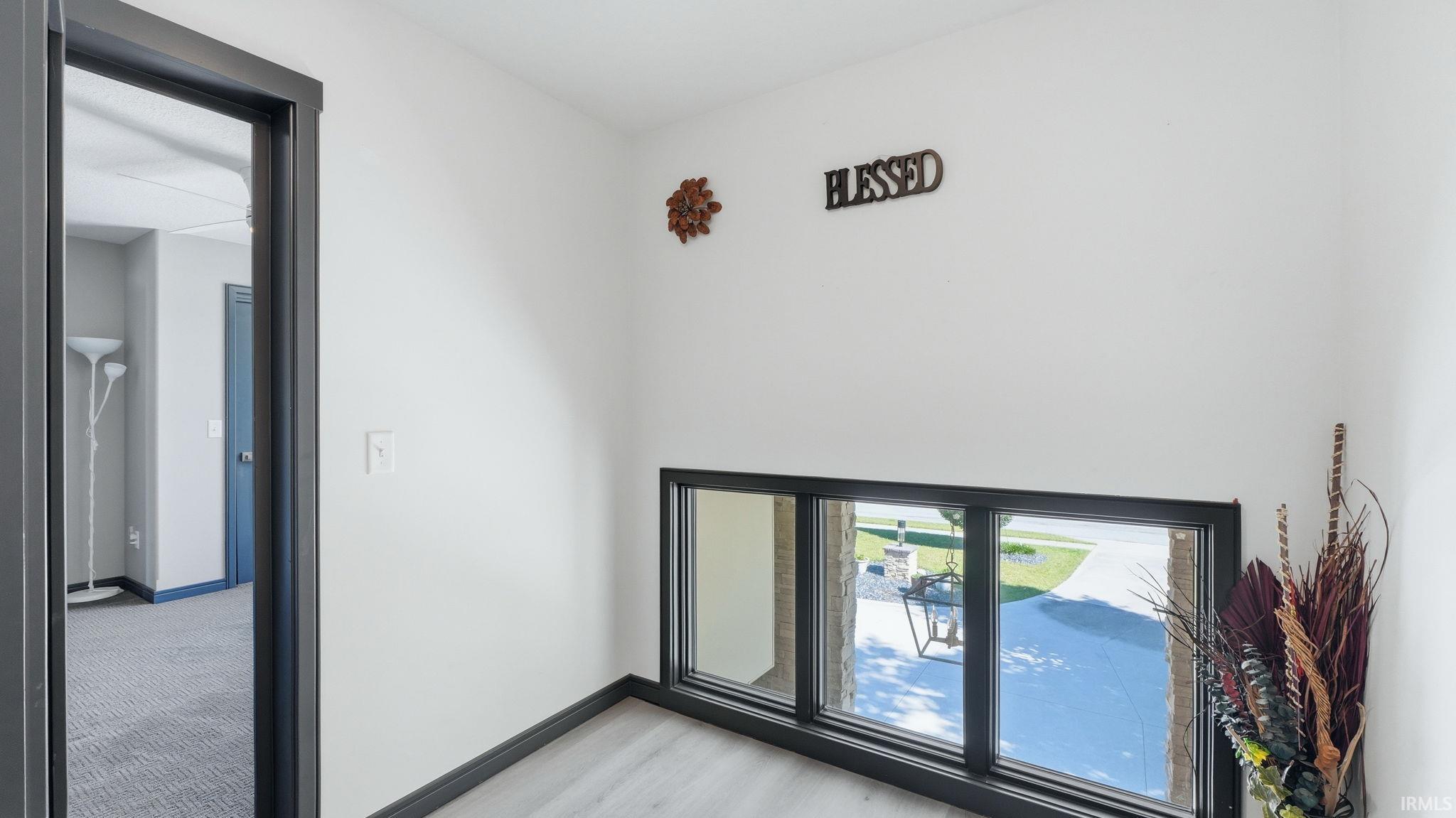 Hallway featuring light wood-finish flooring, white painted walls, and dark trim